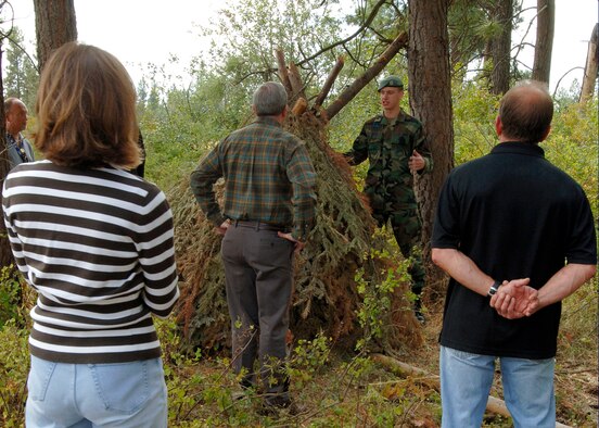 FAIRCHILD AIR FORCE BASE, Wash. – Airman 1st Class Justin Gordon, 22nd Training Squadron Survival, Evasion, Resistance and Escape specialist, explains to Fairchild’s Honorary Commanders how to build a shelter using natural resources in the “back 40” located on the survival side of base Sept. 5. The tour also included water survival helicopter rescue demonstrations. (U.S. Air Force photo / Airman 1st Class Melissa Barnett) 