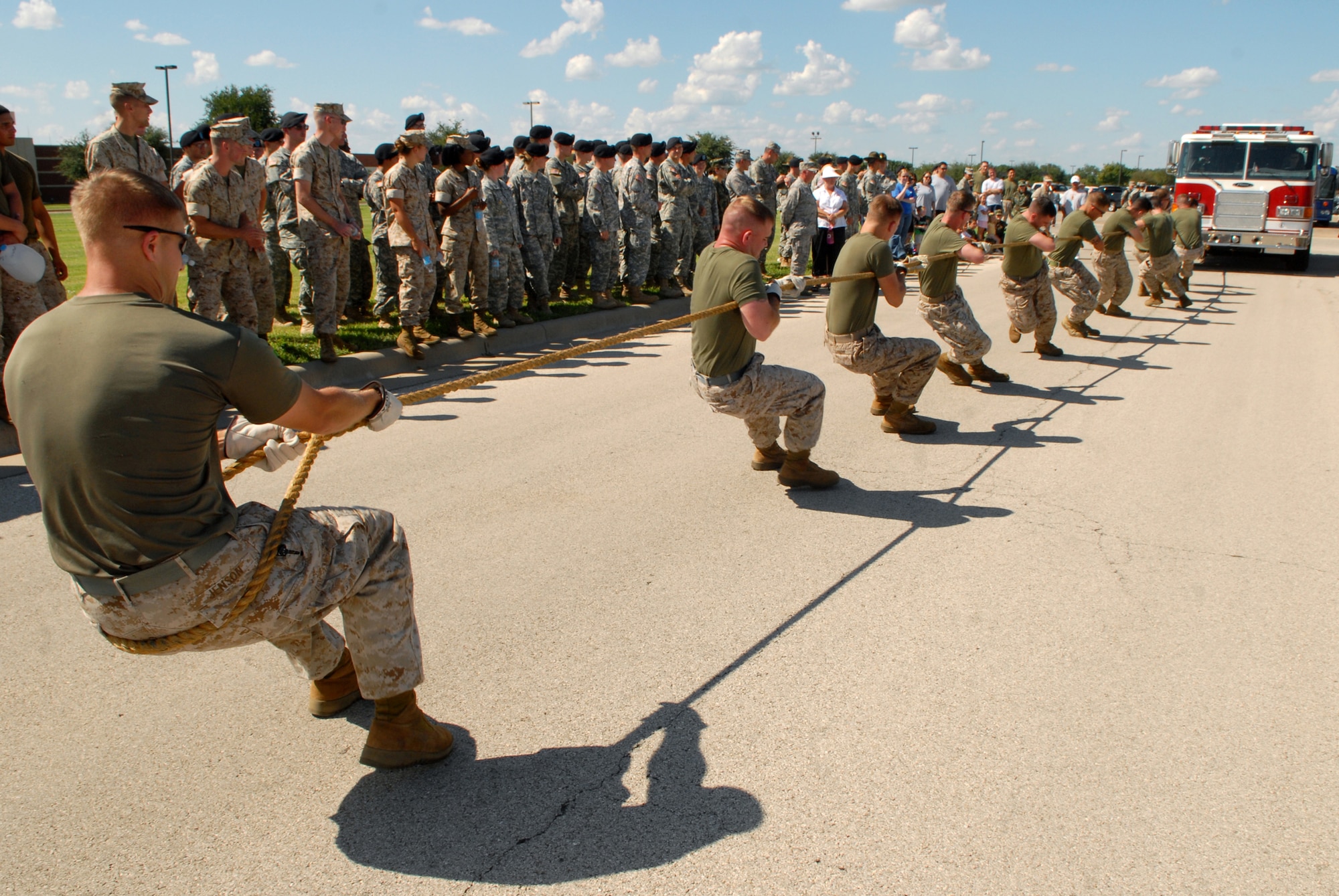 Members of the Marine Detachment Goodfellow team "T for SINGINT" work together to pull a 14.5-ton fire truck 100 feet during a Combined Federal Campaign fundraiser on Goodfellow Air Force Base, Sept. 5.  The overall winning team, "Team Arnold," was also fielded by the Marines, finishing the competition with a winning time of 17.68 seconds. The 316th Training Squadron’s "Jaws XII" took second place with 18 seconds, followed by the Army’s 344th Military Intelligence Battlaion A Company, 3rd Platoon with 18.87 seconds. A total of 31 teams competed in the event. (U.S. Air Force photo by Senior Airman Kasabyan Musal)