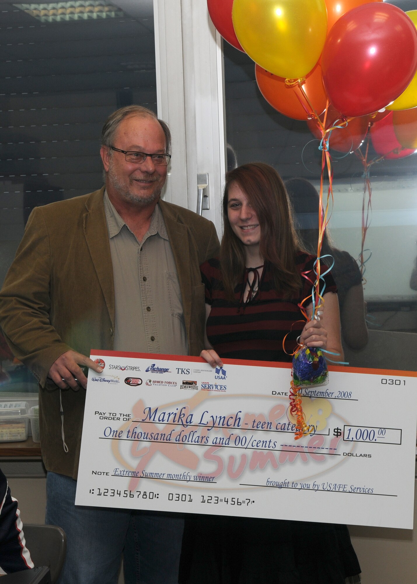SPANGDAHLEM AIR BASE, Germany -- Marika Lynch and her father, William Lynch, hold a $1,000 check at Bitburg Air Base Sept. 12, 2008. Marika was selected for the teen category monthly cash giveaway for her participation in Extreme Summer. (U.S. Air Force photo by Staff Sgt. Heather M. Norris) 