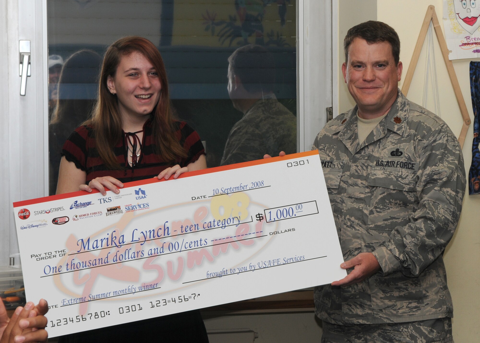 SPANGDAHLEM AIR BASE, Germany -- Maj. Michael Wyatt, 52nd Force Support Squadron commander, presents Marika Lynch a $1,000 check at Bitburg Air Base Sept. 12, 2008, for her participation in Extreme Summer. Marika won the teen category monthly cash giveaway.  (U.S. Air Force photo by Staff Sgt. Heather M. Norris) 