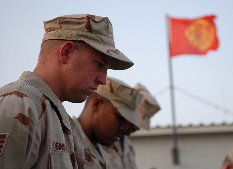 SOUTHWEST ASIA -- Staff Sgt. Mitchell Robinson, 380th Expeditionary Civil Engineer Squadron, bows his head during a moment of silence. Sergeant Robinson headed up a a team who built and organized a display case to house an authentic New York police officer uniform and a structural firefighiing uniform. The display was unveiled at the Patriot Day ceremony to commemorate the fallen responders from the 2001 terrorist attacks. (U.S. Air Force photo/Tech. Sgt. Denise Johnson)(released)