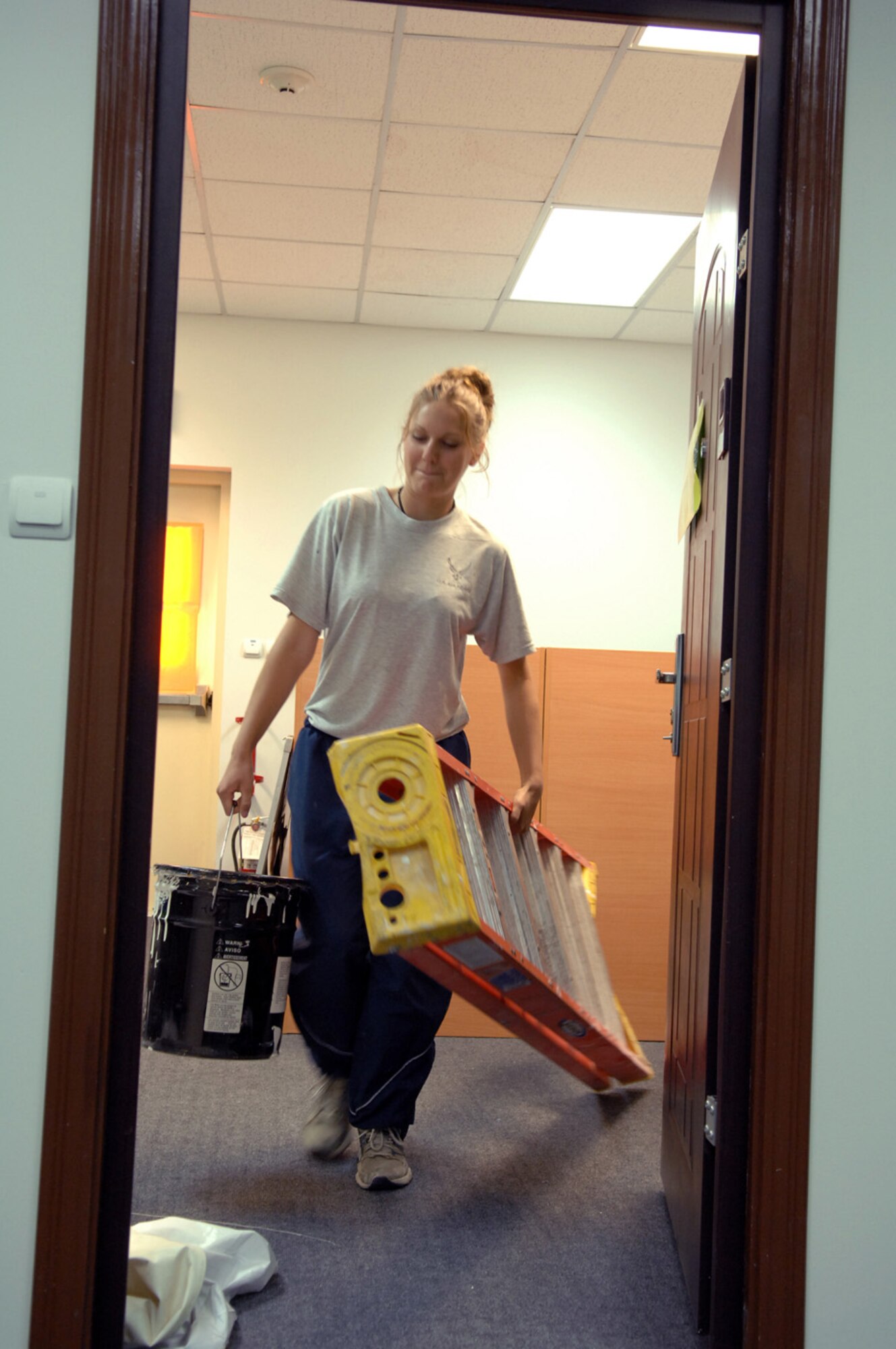 Senior Airman Alison Osborn, 376th Expeditionary Forces Support Squadron technician and Manas Learning Resource Center staff member, carries supplies into the last LRC room needing paint. The staff of the LRC worked hard to provide customer suggested improvements to the center like fresh paint and new carpeting. (Air Force photo / Tech. Sgt. Michael Voss)