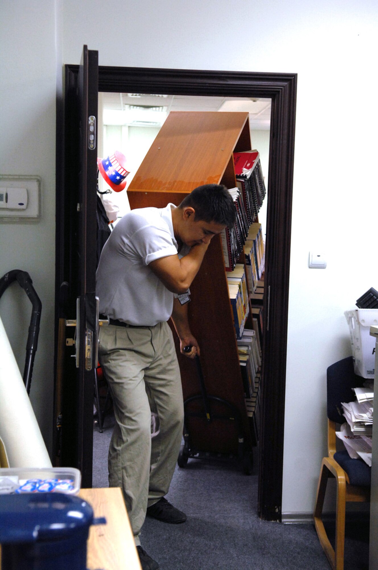 Kuvan Nuraliev, Gulf Catering Company contractor and member of the Manas Learning Resource Center staff, maneuvers a bookshelf full of books and DVDs into the newly renovated LRC. The staff of the LRC worked hard to provide customer suggested improvements to the center like fresh paint and new carpeting. (Air Force photo / Tech. Sgt. Michael Voss)