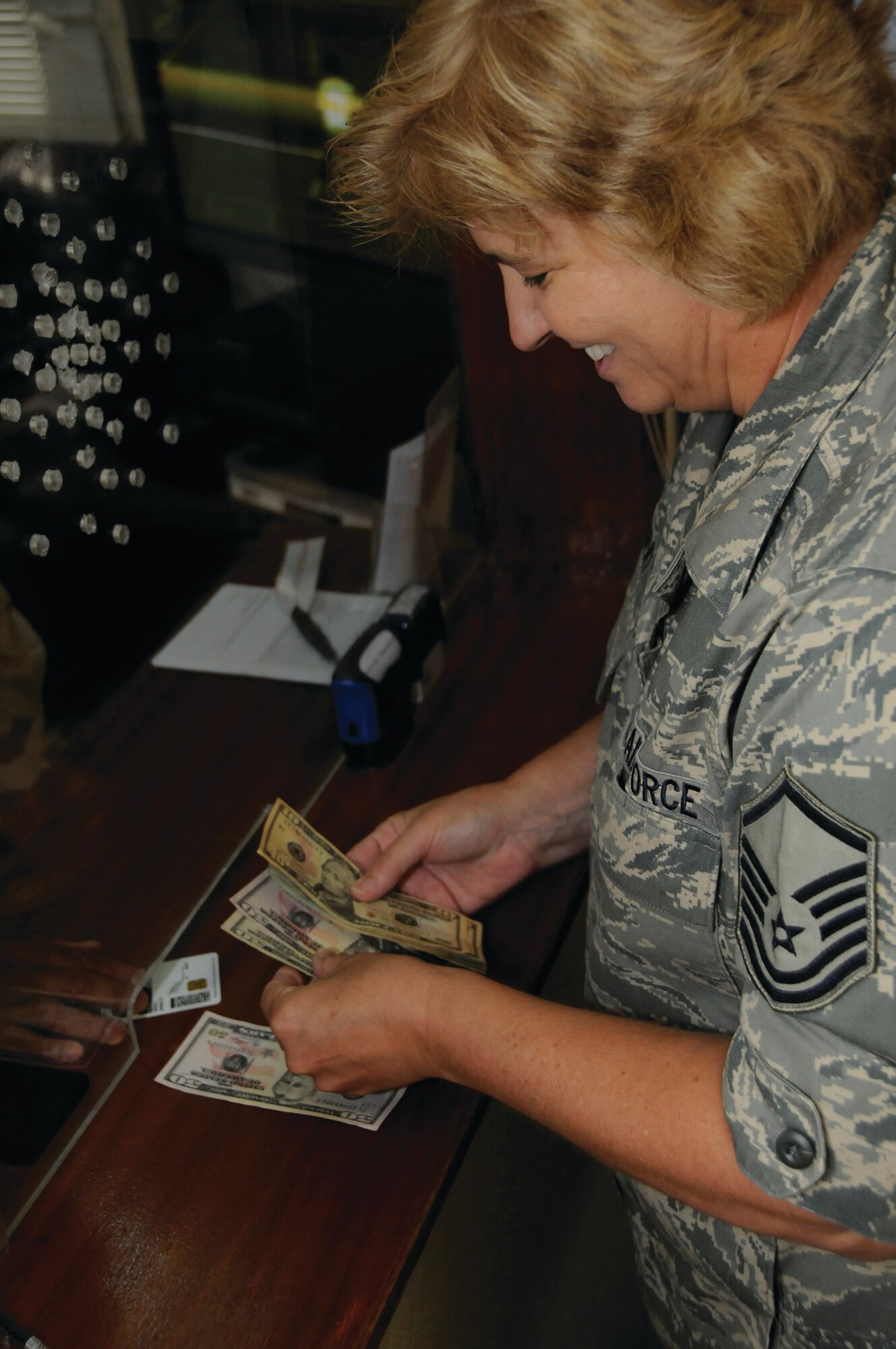 Master Sgt. Anna Gray, cashier for the 379th Expeditionary Comptroller Squadron, cashes a check for a customer here Sept. 8. The 379th ECPTS finance section cashes checks and exchanges currency for those here and handles pay entitlements for the entire area of responsibility. Last month the section hepled about 4,900 customers. The squadron also manages the 379th Air Expeditionary Wing’s $94.7 million budget. Sergeant Gray, a native of Tulsa, Okla., is deployed from the Oklahoma Air National Guard. (U.S. Air Force photo by Staff Sgt. Darnell T. Cannady)
