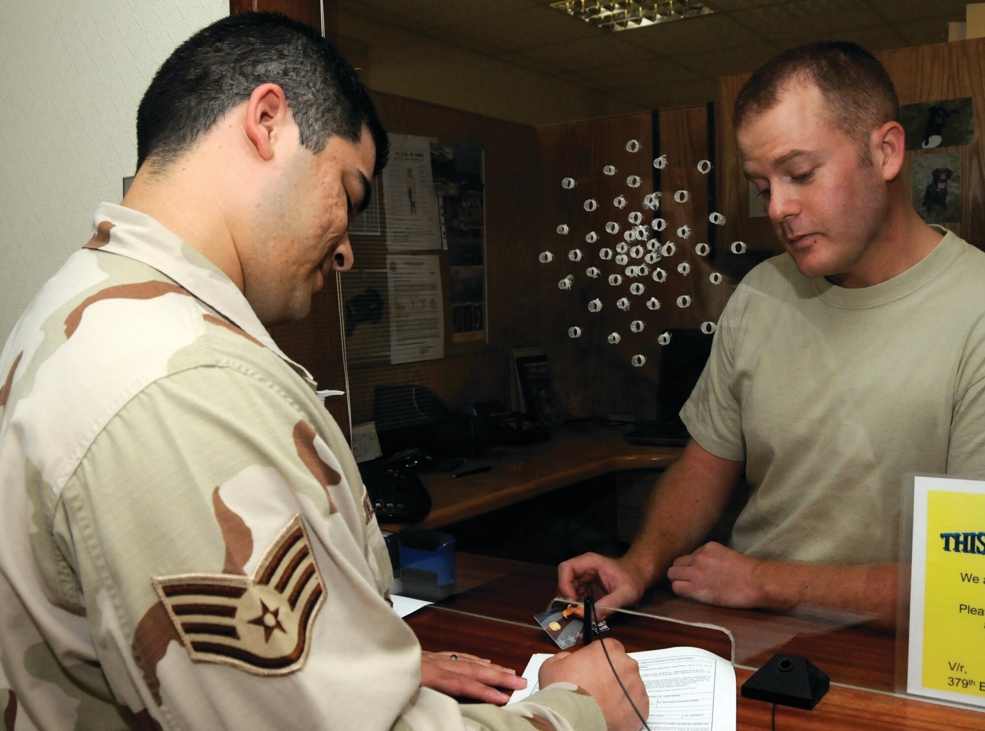Staff Sgt. Benjamin King, right, cashier assigned to the 379th Expeditionary Comptroller Squadron, assists a customer in processing paperwork to get an Eagle Cash Card here Sept. 3. The Eagle Cash Card became mandatory for all deployed members Aug. 1. Sergeant King, a native of Waldorf, Md., is deployed from Ellsworth Air Force Base, S.D.  (U.S. Air Force photo by Staff Sgt. Darnell T. Cannady)