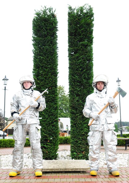 Base Firefighters Airman Kenneth Colton, left, with pike pole, and Senior Airman Jayton Washington, with axe, stand at ease at the end of the Sept. 11 memorial service at RAF Mildenhall, England, Sept. 11, 2008. (U.S. Air Force photo by Karen Abeyasekere)