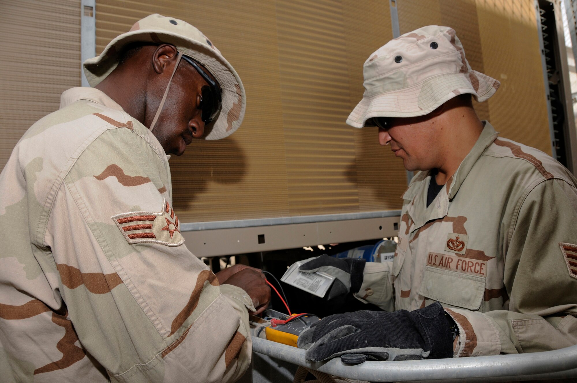 Senior Airman Lamar Reece, 379th Expeditionary Civil Engineer Squadron, checks current through a chill water valve to test power on an air conditioning unit Sept. 11, 2008.  Staff Sgt. Danny Garcia, 379 ECES, checks values that are supposed to be present at this juncture.  Sergeant Garcia and Airman Reece are trying to restore power to the chiller at the Base Exchange in the Blatchford-Preston Complex.  The Heating Ventilation and Air Conditioning shop is in charge of maintenance of all air conditioning units at this undisclosed location in Southwest Asia.  Sergeant Garcia is deployed from McChord Air Force Base, Wash., and Airman Reece is deployed from Pope AFB, N.C. Both are here supporting Operations Iraqi and Enduring Freedom and Joint Task Force-Horn of Africa.  (U.S. Air Force photo by Tech. Sgt. Michael Boquette/Released)