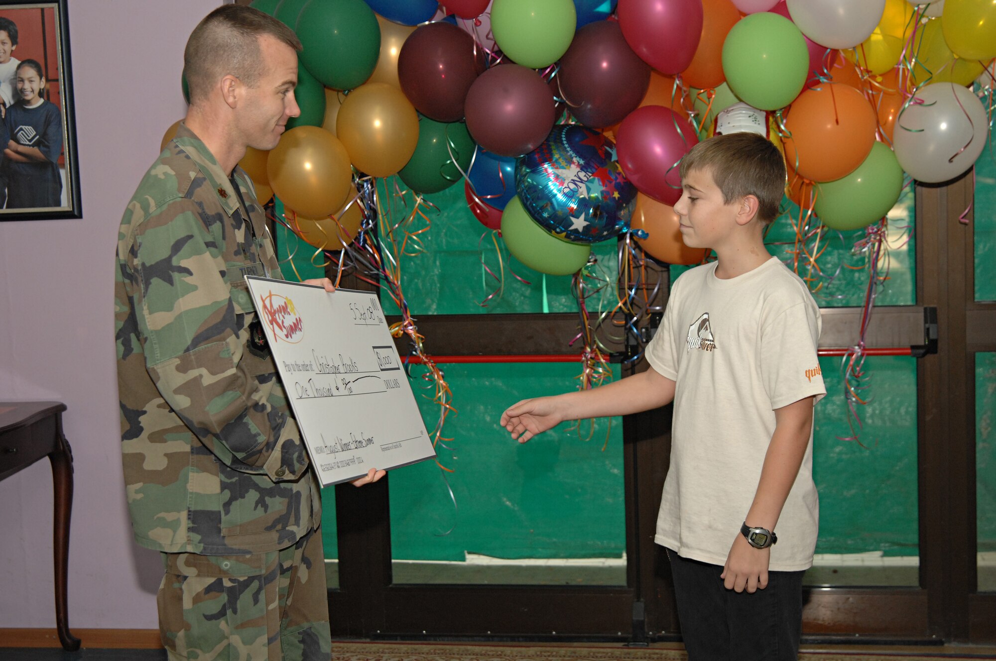 Christopher Brooks accepts a $1,000 check from Maj. James Turner, 39th Force Support Squadron commander, as one of the prizes awarded during August for participating in this year’s Extreme Summer, Sept. 5. (U.S. Air Force photo by Senior Airman Benjamin Wilson)