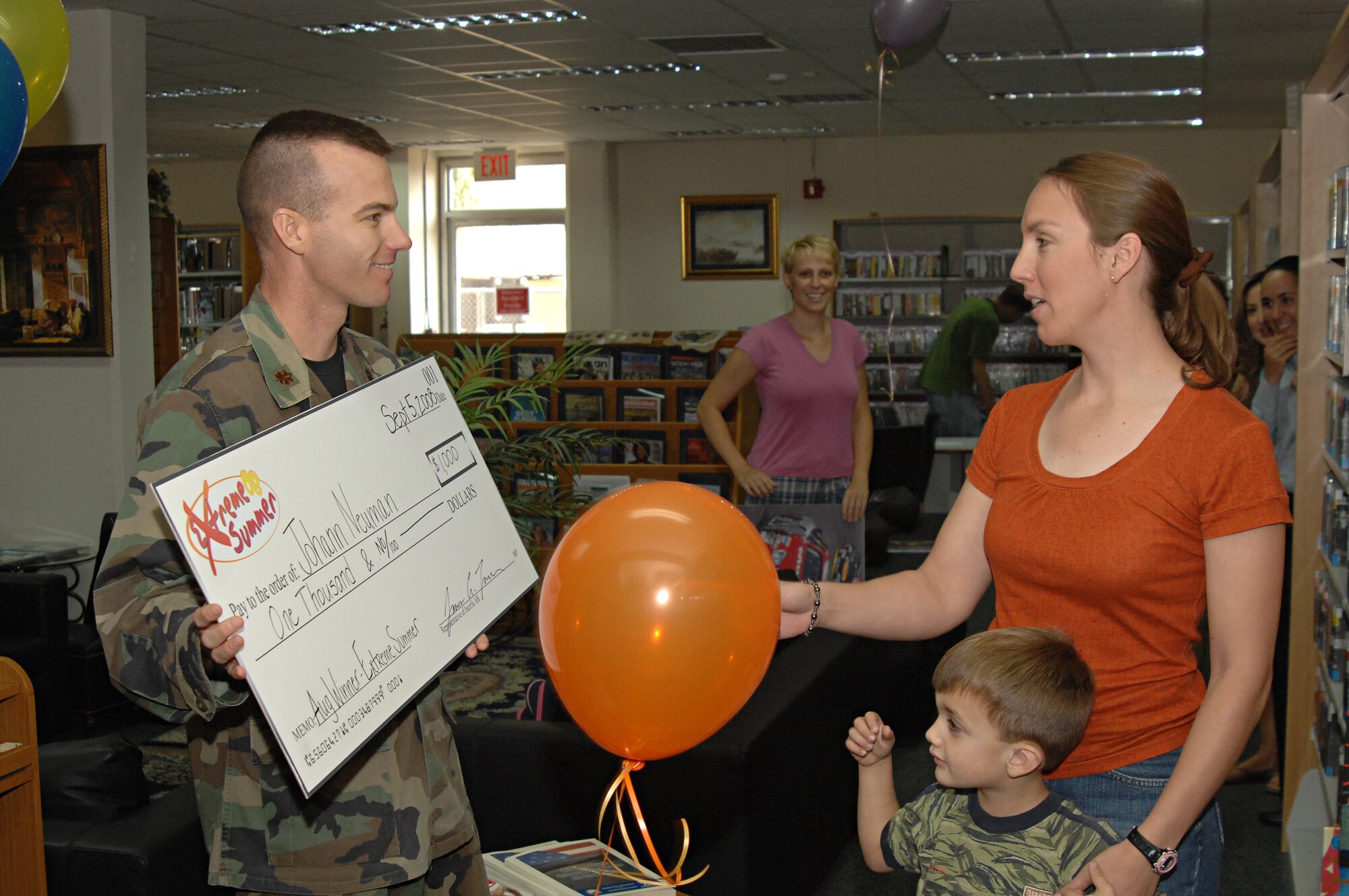 Carol Neuman accepts a $1,000 check from Maj. James Turner, 39th Force Support Squadron commander, on behalf of her husband Special Agent Johann Neuman as one of the prizes awarded during August for participating in this year’s Extreme Summer, Sept. 5. (U.S. Air Force photo by Senior Airman Benjamin Wilson)