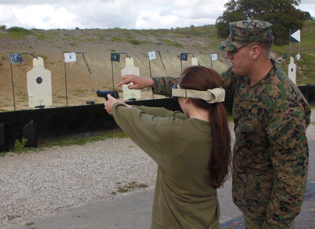 Marine spouse Tamra Williams is learning how to fire the M-9 service pistol from Cpl. Michael McDowell, marksmanship coach, Headquarters and Support Battalion, Marine Corps Base Camp Pendleton, at Range 213 during the, the unit's annual Jane Wayne Day, March 13. The spouses had the full “Marine experience” by learning some techniques from the Marine Corps Martial Arts Program, climbing the rope of the obstacle course, firing numerous weapon systems, participating in the combat fitness test and several other activities.