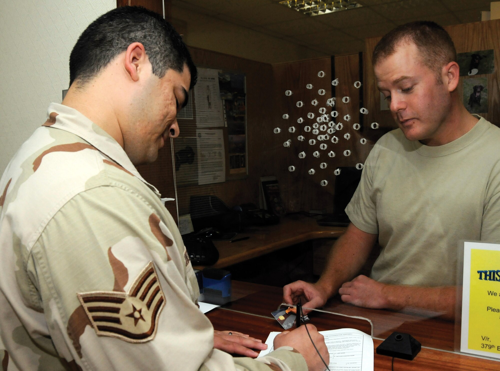 Staff Sgt. Benjamin King, right, assists a customer in processing paperwork to get an Eagle Cash Card in Southwest Asia Sept. 3. The Eagle Cash Card became mandatory for all deployed members Aug. 1. Sergeant King is a cashier assigned to the 379th Expeditionary Comptroller Squadron. (U.S. Air Force photo/Staff Sgt. Darnell T. Cannady) 
