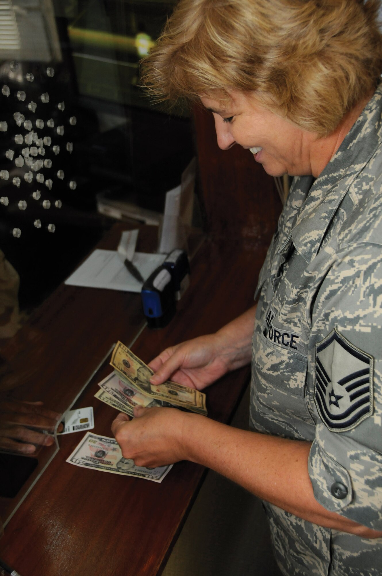 Master Sgt. Anna Gray cashes a check for a customer in Southwest Asia Sept. 8. The 379th Expeditionary Comptroller Squadron finance section cashes checks and exchanges currency for those here and handles pay entitlements for the entire area of responsibility. Last month the section helped about 4,900 customers. The squadron also manages the 379th Air Expeditionary Wing's $94.7 million budget. Sergeant Gray is a cashier for the 379th ECPTS. (U.S. Air Force photo/Staff Sgt. Darnell T. Cannady)