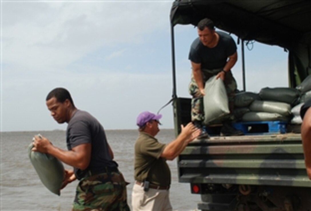 Plaquemines Parish Land Superintendent Blair G. Rittiner and Louisiana Air National Guard Staff Sgts. Justin T. Barquet and Gene Monteilh, 159th Fighter Wing, place sandbags on a levee that protects Highway 23, which serves as the main road in Plaquemines Parish, Sept. 11, 2008. 