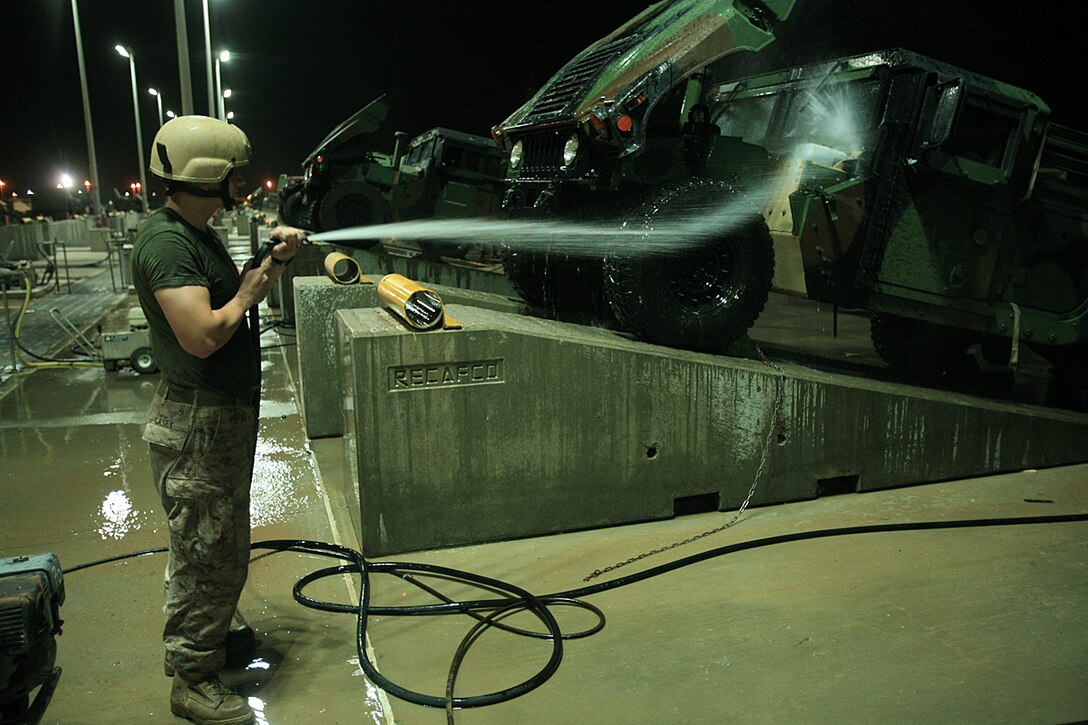 A Marine with the 15th Marine Expeditionary Unit uses a pressure sprayer to clean dirt and debrit from a high mobility multipurpose vehicle.::r::::n::The 15th MEU's vehicles and equipment were required to meet the US Central Command's customs and agricultural standards before being re-embarked aboard ships prior to returning to the Continental United States.(Official USMC photo by Staff Sgt. TG Kessler)(Released)