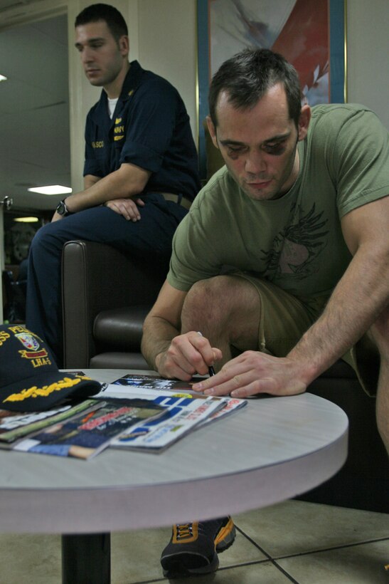 Ultimate Fighting Championship star Rich Franklin signs autographs in the officers lounge aboard USS Peleliu (LHA 5) during a morale visit to visit the Marines of the 15th Marine Expeditionary Unit and crew of USS Peleliu in the Northern Persian Gulf.::r::::n::   Both Rich Franklin and Tim Sylvia of the UFC came aboard USS Peleliu during an 11-day tour of the Middle East sponsored by the Navy's Morale, Welfare and Recreation program to encourage troops deployed in this region and to meet with fans.::r::::n::   The Camp Pendleton, Calif. based 15th MEU is comprised of approximately 2,200 Marines and Sailors and is a forward deployed force of readiness capable of conducting numerous operations, such as Non-Combatant Evacuation Operations, Humanitarian Assistance Operations and a wide range of amphibious missions. ::r::::n::   The 15th MEU is currently deployed in the Persian Gulf region. (Official USMC photo by Cpl. Timothy T. Parish) (Released)