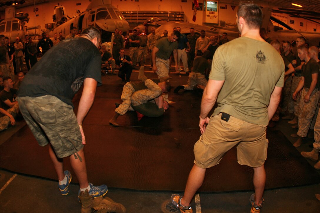 Ultimate Fighting Championship stars Rich Franklin and Tim Sylvia watch a Marine Corps Martial Arts demonstration by the Marines of Golf Company, Battalion Landing Team 2/5, 15th MEU during a morale visit with the Marines of the 15th MEU and crew of USS Peleliu in the hangar bay aboard USS Peleliu in the Northern Persian Gulf.::r::::n::   Both Rich Franklin and Tim Sylvia of the UFC came aboard USS Peleliu during an 11-day tour of the Middle East sponsored by the Navy's Morale, Welfare and Recreation program to encourage troops deployed in this region and to meet with fans.::r::::n::   The Camp Pendleton, Calif. based 15th MEU is comprised of approximately 2,200 Marines and Sailors and is a forward deployed force of readiness capable of conducting numerous operations, such as Non-Combatant Evacuation Operations, Humanitarian Assistance Operations and a wide range of amphibious missions. ::r::::n::   The 15th MEU is currently deployed in the Persian Gulf region. (Official USMC photo by Cpl. Timothy T. Parish) (Released)