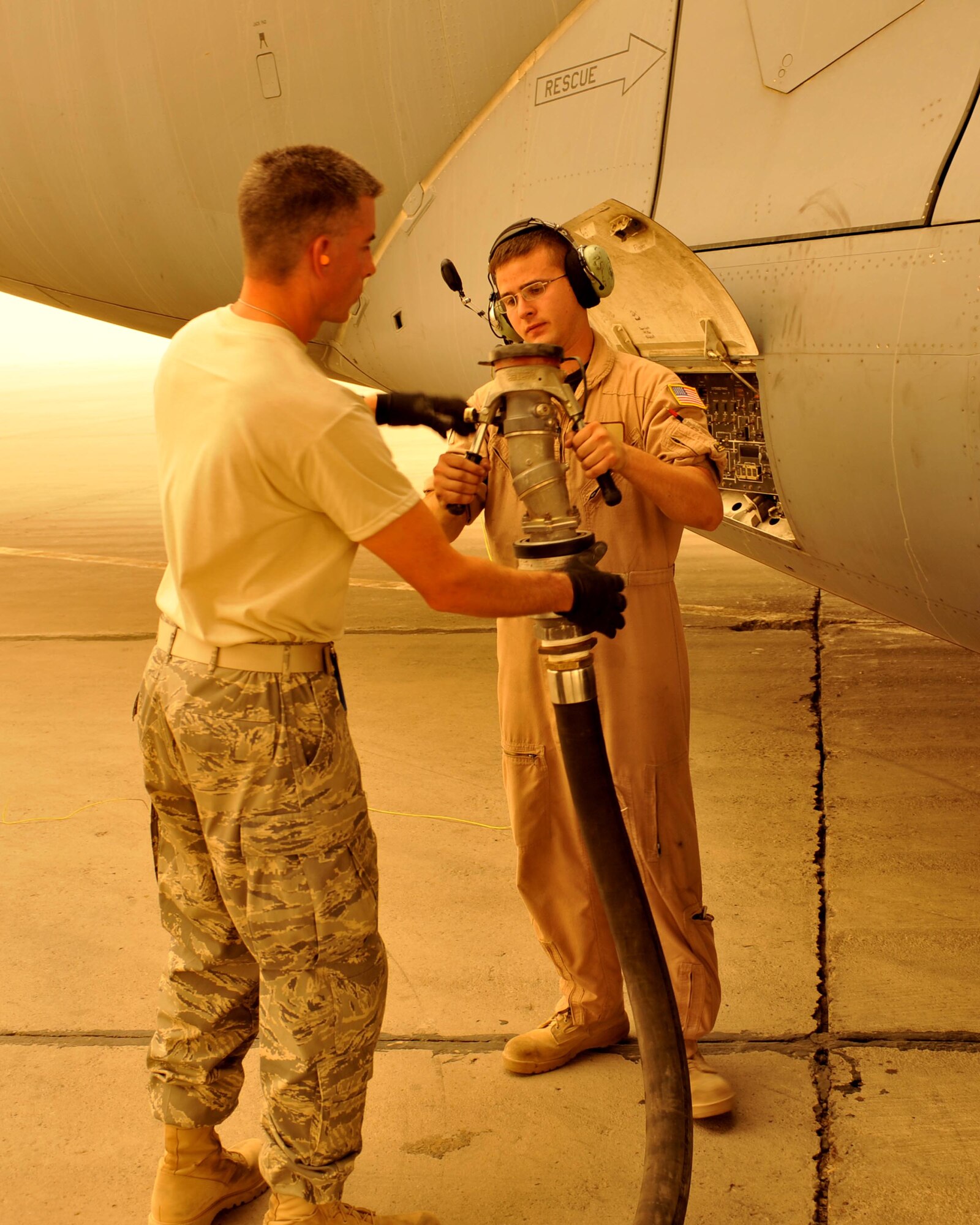 9/14/2008 ? SATHER AIR BASE, Iraq ? Master Sgt. Steve Hoenig (left), a fuels specialist assigned to the 447th Expeditionary Logistics Readiness Squadron, and crew chief Senior Airman Chris Magee from the 182nd Airlift Squadron at Ali Al Salem Air Base, Kuwait fuel a C-17 Globemaster III aircraft at Sather Air Base on the west side of Baghdad International Airport. A dust storm brought visibility down to less than 1,000 meters, but the C-17 was able to take off before conditions deteriorated and stopped air travel around the Baghdad area. Sergeant Hoenig is an Illinois Air National Guard member deployed from the 182nd Airlift Wing in Peoria. Airman Magee is deployed from the 305th Aircraft Maintenance Squadron at McGuire Air Force Base, N.J. (U.S. Air Force photo by Master Sgt. Brian Davidson)