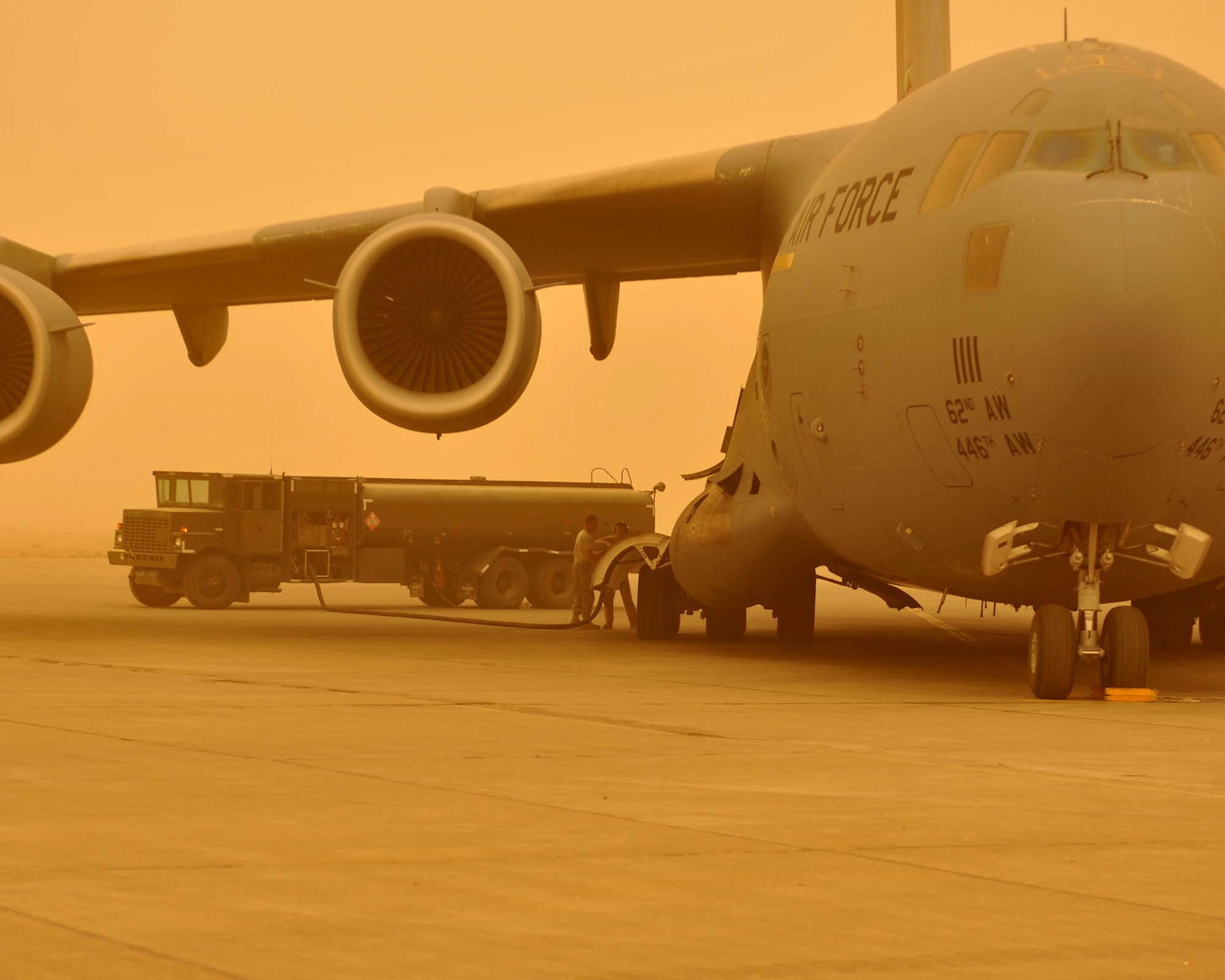 9/14/2008 ? SATHER AIR BASE, Iraq ? Master Sgt. Steve Hoenig (left), a fuels specialist assigned to the 447th Expeditionary Logistics Readiness Squadron, and crew chief Senior Airman Chris Magee from the 182nd Airlift Squadron at Ali Al Salem Air Base, Kuwait fuel a C-17 Globemaster III aircraft at Sather Air Base on the west side of Baghdad International Airport. A dust storm brought visibility down to less than 1,000 meters, but the C-17 was able to take off before conditions deteriorated and stopped air travel around the Baghdad area. Sergeant Hoenig is an Illinois Air National Guard member deployed from the 182nd Airlift Wing in Peoria. Airman Magee is deployed from the 305th Aircraft Maintenance Squadron at McGuire Air Force Base, N.J. (U.S. Air Force photo by Master Sgt. Brian Davidson)