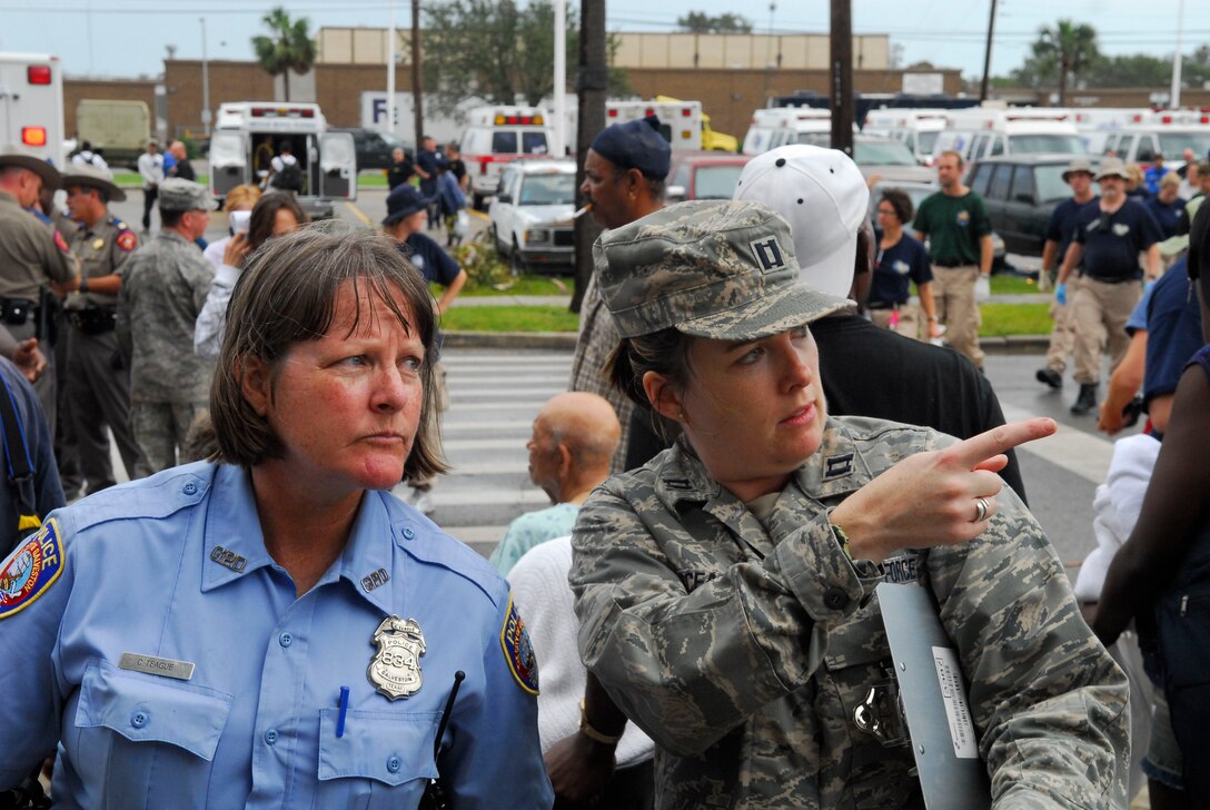 Officer C. Teague of the Galveston Police Department and Captain Shelly Garceau of the Texas Air National Guard's 149 Fighter Wing assist post landfall Hurricane Ike evacuees from Ball High School in Galveston. The people will be transported by bus to evacuation hubs in San Antonio. (U.S. Air Force photo Master Sgt. Robert Shelley)