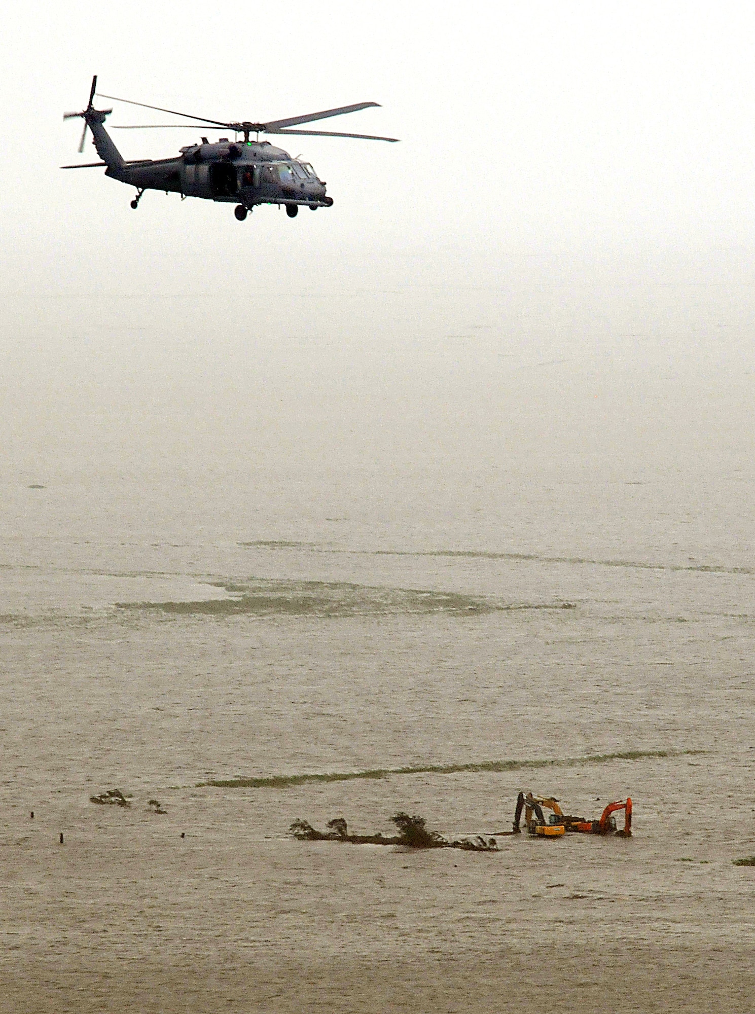 GULF OF MEXICO -- An Air Force Reserve HH-60G Pave Hawk helicopter from the 920th Rescue Wing passes over three massive hydraulic excavators lost to flood waters from Hurricane Ike. Deployed from their home at Patrick AFB, Fla., the Resersve aircrews, equipped with two HH-60G Pave Hawk helicopters and two HC-130P/N refueling aircraft, saved 17 people from the devastation of Ike. (U.S. Air Force photo/Tech. Sgt. Paul Flipse)