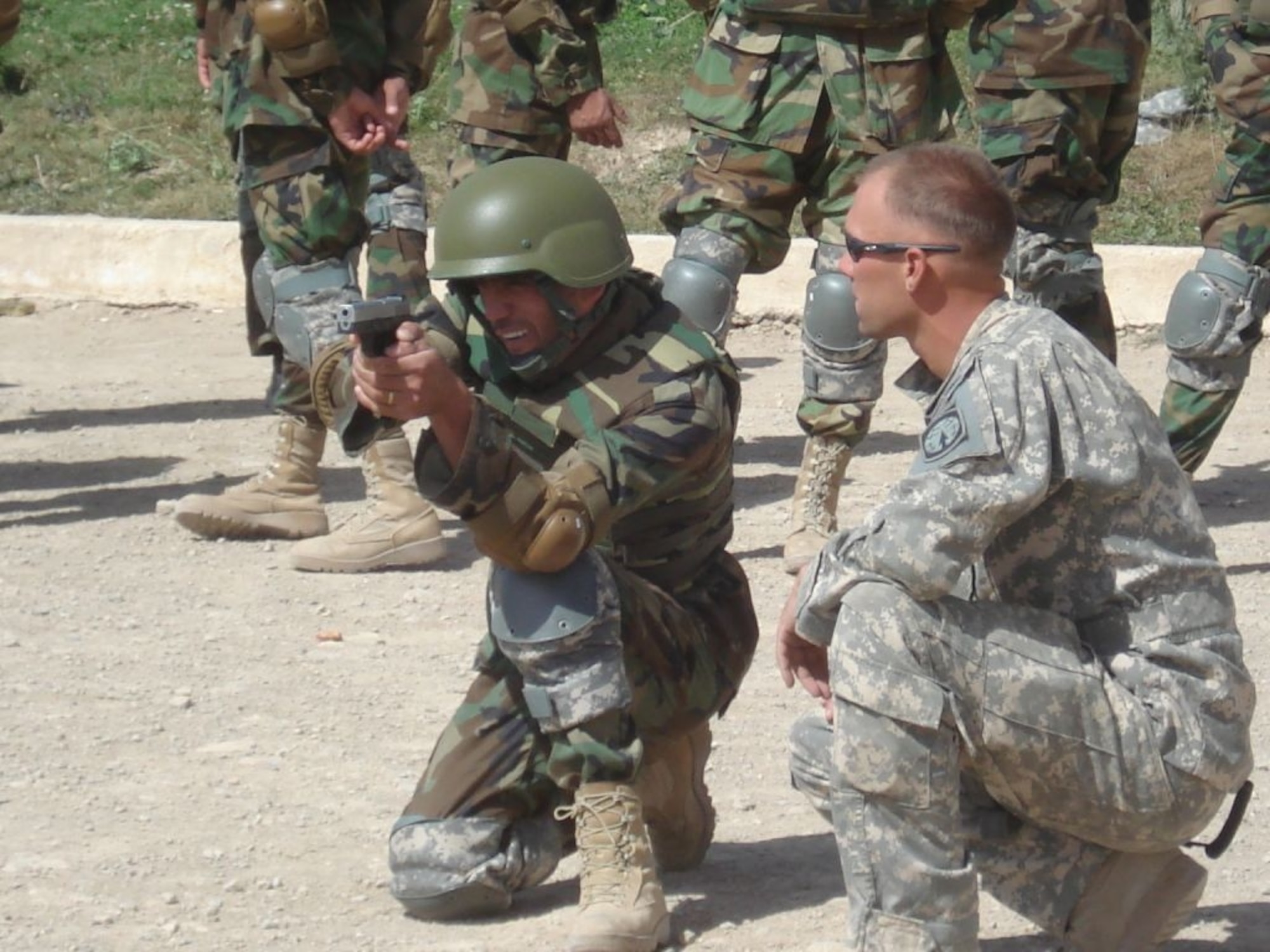 Sgt. Adam Zimmerman, a native of Sylvania, Ohio, coaches ANA Staff Sgt. Assadullah Abdul Saleem on proper 9mm firing techniques during a weapons familiarization class. (U.S. Army photo by Capt. Mike Miranda)