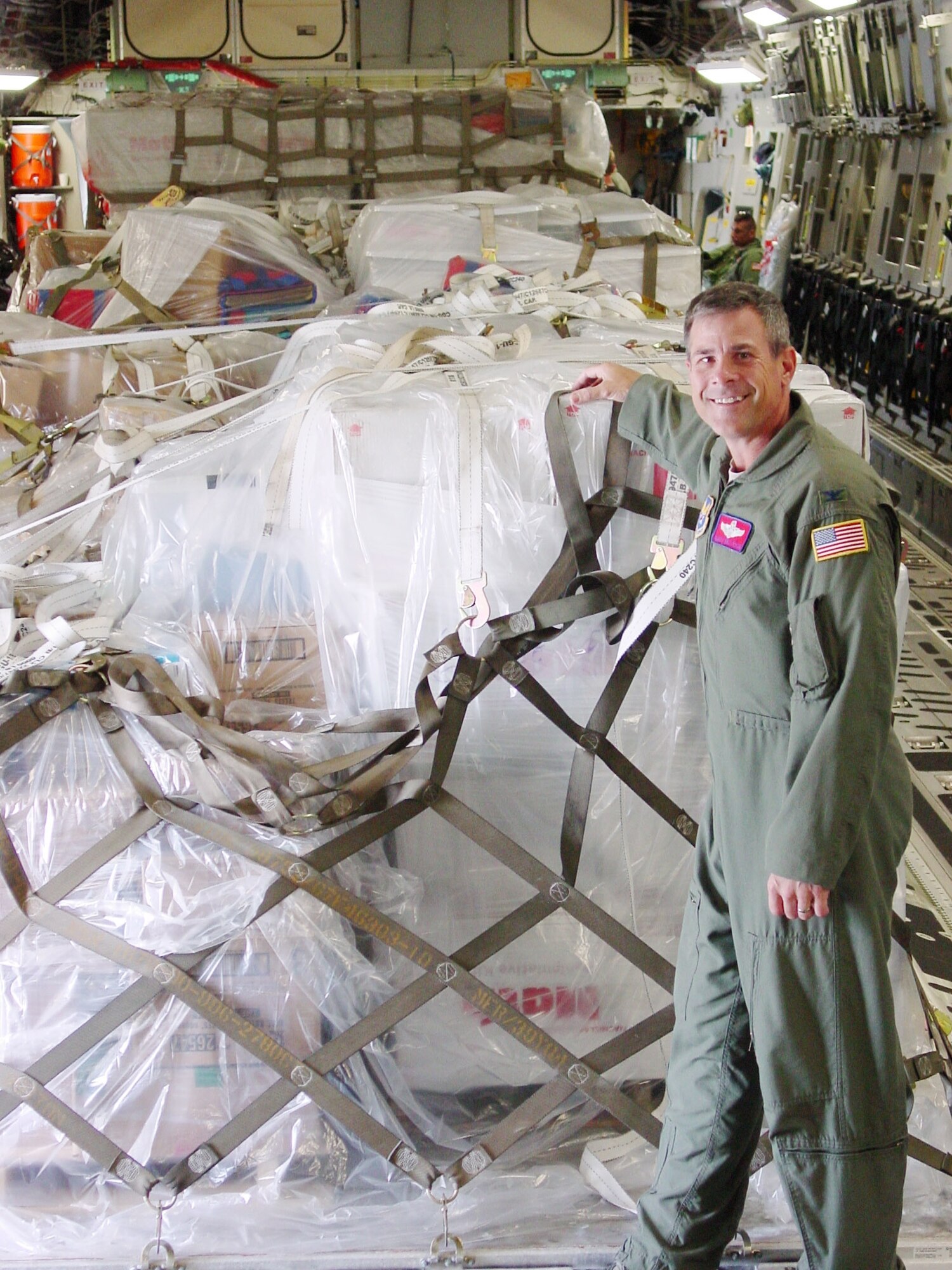 Col. John Wojtysiak stands in front of the books that were donated in support of a humanitarian relief mission.  (U.S. Air Force photo)