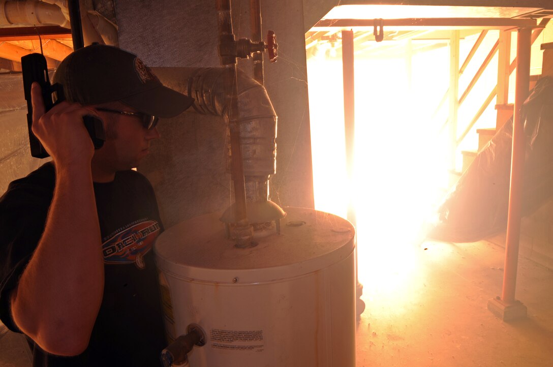 A “flash bang” stun grenade detonates in the basement of a house where Ryan McCandless, Rapid City Police Department police officer, pretends to be an armed perpetrator during a special weapons and tactics exercise on Sept. 12. “Flash bangs” are designed to confuse, disorient or momentarily distract a potential threat. (U.S. Air Force photo/Senior Airman Marc I. Lane)