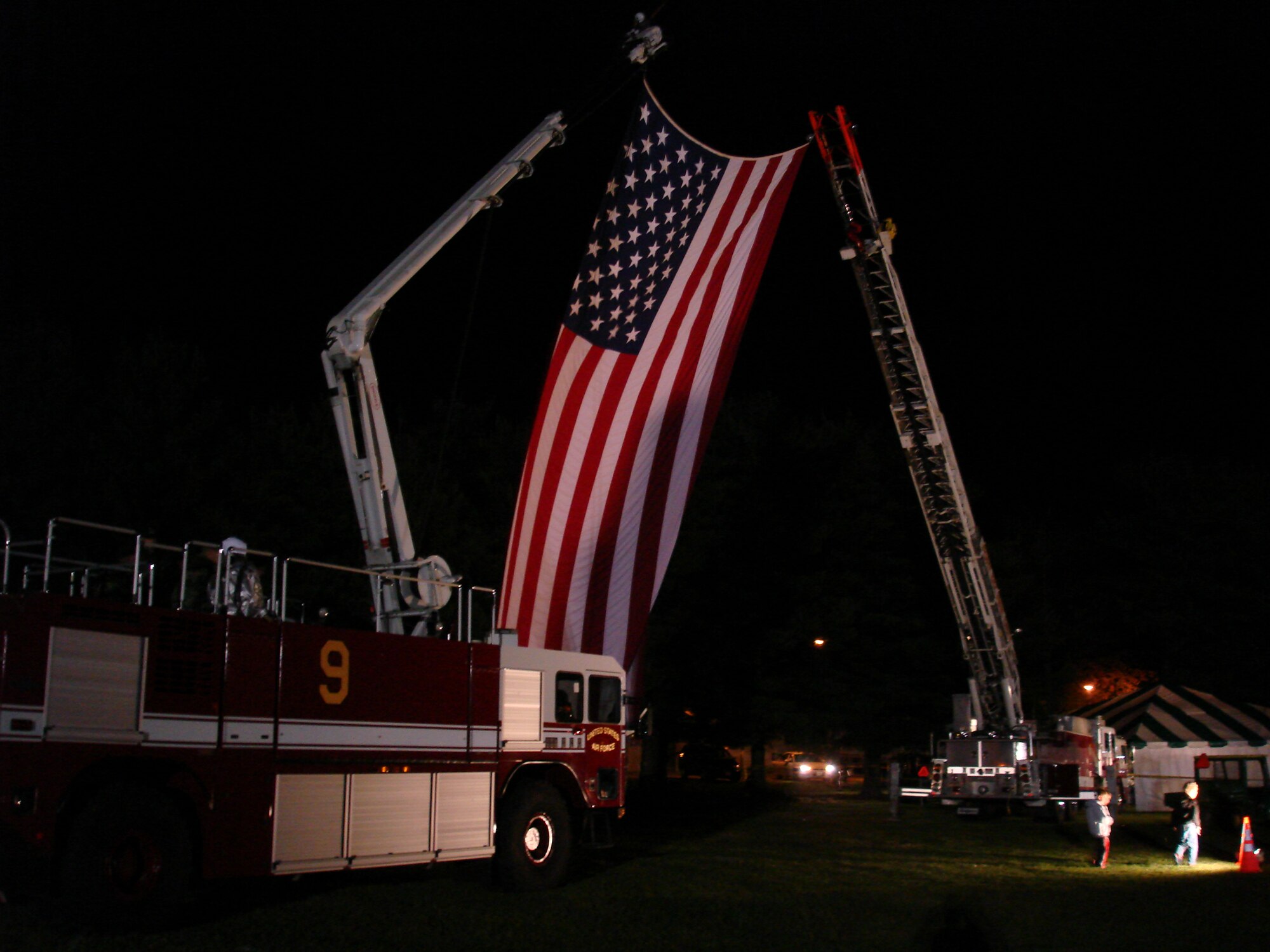 McGuire and Fort Dix fire trucks raise the American flag Sept. 11 at Doughboy Field during a concert held by the country band Lonestar. The concert was held to pay tribute to those who lost their lives Sept. 11, 2001. More than 300 personnel from McGuire, Fort Dix and Lakehurst attended the concert. (U.S. Air Force photo/Staff Sgt. Frank Lalic)  