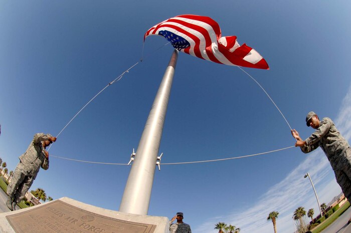 Senior Airmen Jerome Fontenot (left), 57th Aircraft Maintenance Squadron F-16 crew chief and Staff Sgt. Joseph Suarez (right), 99th Medical Operations Squadron physical therapy technician, lower the nations colors during a retreat ceremony at Nellis Air Force Base, Nev., Sept. 11, 2008. The airmen are part of a four man flag detail team that raised and retired the colors, honoring those who gave their all during Sept. 11, 2001.(U.S. Air Force Photo/Senior Airman Larry E. Reid Jr.)