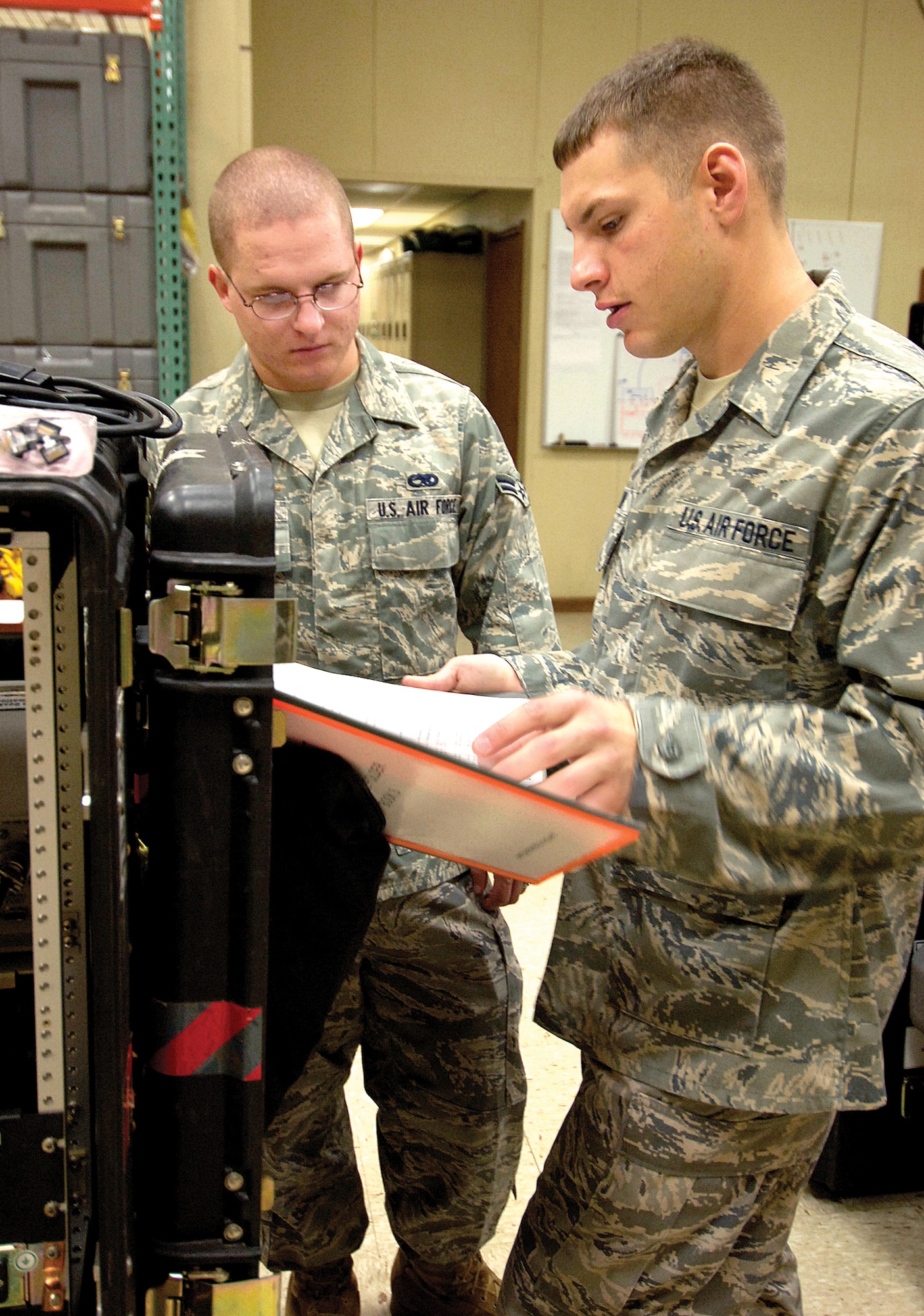 Senior Airman David Honey, front, shows Airman First Class Benjamin Bowles some of the equipment the 32 Combat Communications Squadron Airmen use when setting up bare base communications in deployed locations.  Airman Honey is Airman Bowles’ sponsor and will help him make a smoother transition to his new life at Tinker and with the 32nd CCS.(Air Force photo/Margo Wright)
