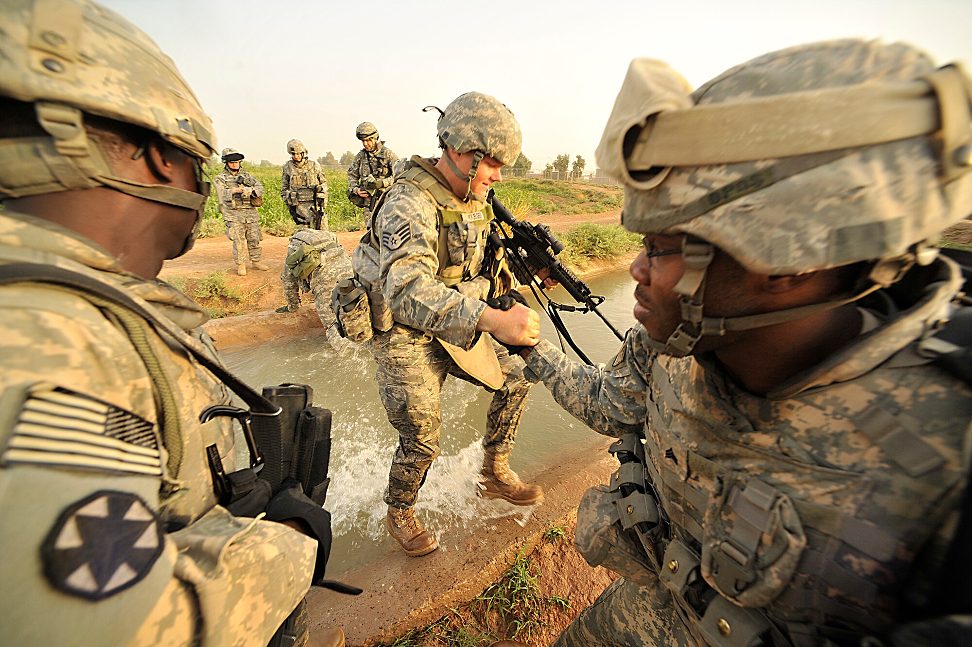U.S. Army Soldiers help Air Force Staff Sgt. Johnathon Krueger, 332nd Expeditionary Security Forces Squadron, across a irrigation canal outside Joint Base Balad, Iraq during Operation Lewis and Clark Sept. 11. Operation Lewis and Clark was a joint patrol in which Air Force security forces Airmen were introduced to Balad's outer perimeter. Since Americans began operating from Balad in 2003, the Army has been responsible for base security. The 332nd ESFG will soon be the largest security forces unit deployed in combat to defend an airbase since Vietnam. 
(U.S. Air Force photo by Staff Sgt. Aaron Allmon) 
