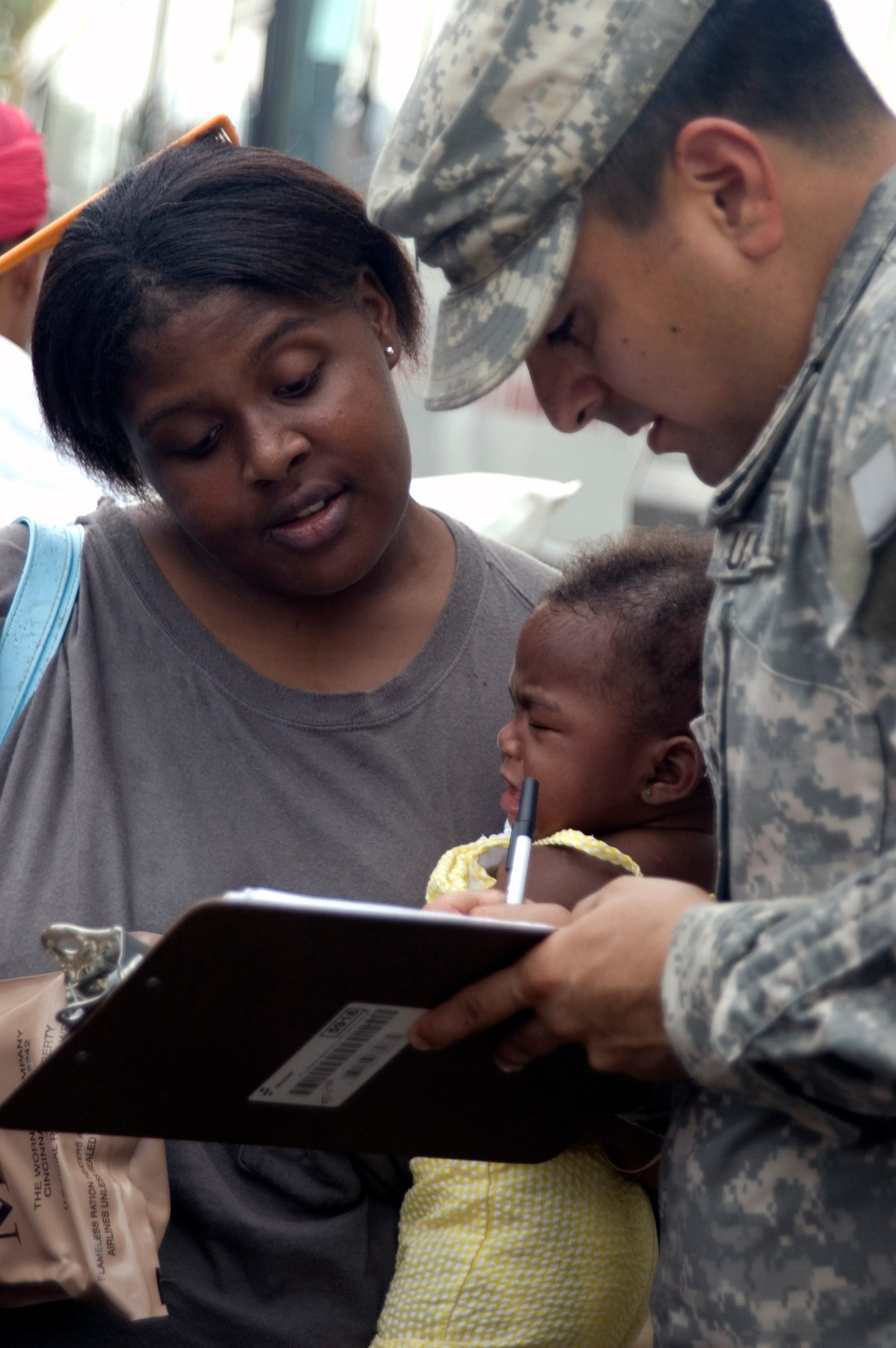Army Spc. Jacob Mireles asks an evacuee for identification information before she boarded a bus to San Antonio Sept. 14. Approximately 1,000 people boarded buses after Galveston, Texas, received heavy flooding, power and water outage due to Hurricane Ike. Specialist Mireles is from the 162th Area Support Medical Company, Texas Army National Guard. (U.S. Air Force photo/Tech. Sgt. Matthew McGovern)