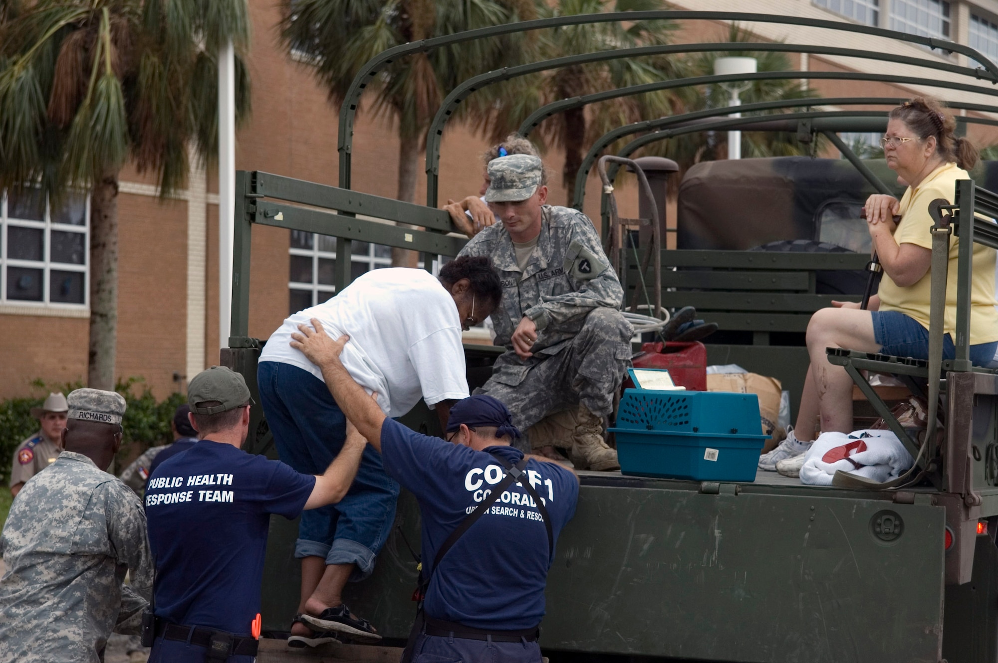 Joint responders assist people from five-ton vehicles at a local high school in Galveston, Texas, before being be bused to San Antonio. (U.S. Air Force photo/Tech. Sgt. Matthew McGovern)