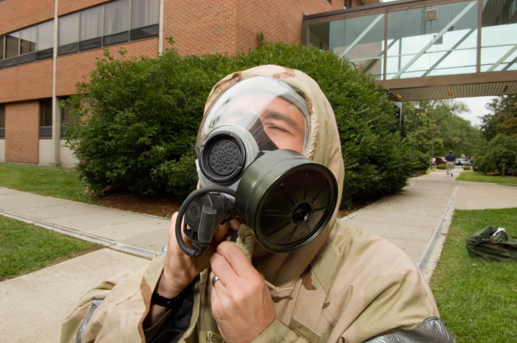 HANSCOM AFB, Mass. -- An Airman fastens his hood around his gas mask during the 551st Electronic Systems Wing's Warrior Day Sept. 12. During the day's events, Airmen practiced various battlefield skills including weapons handling, Self Aid and Buddy Care techniques and wearing Mission Oriented Protective Posture gear, which protects wearers from chemical and biological agents. (U.S. Air Force photo by Mark Wyatt)