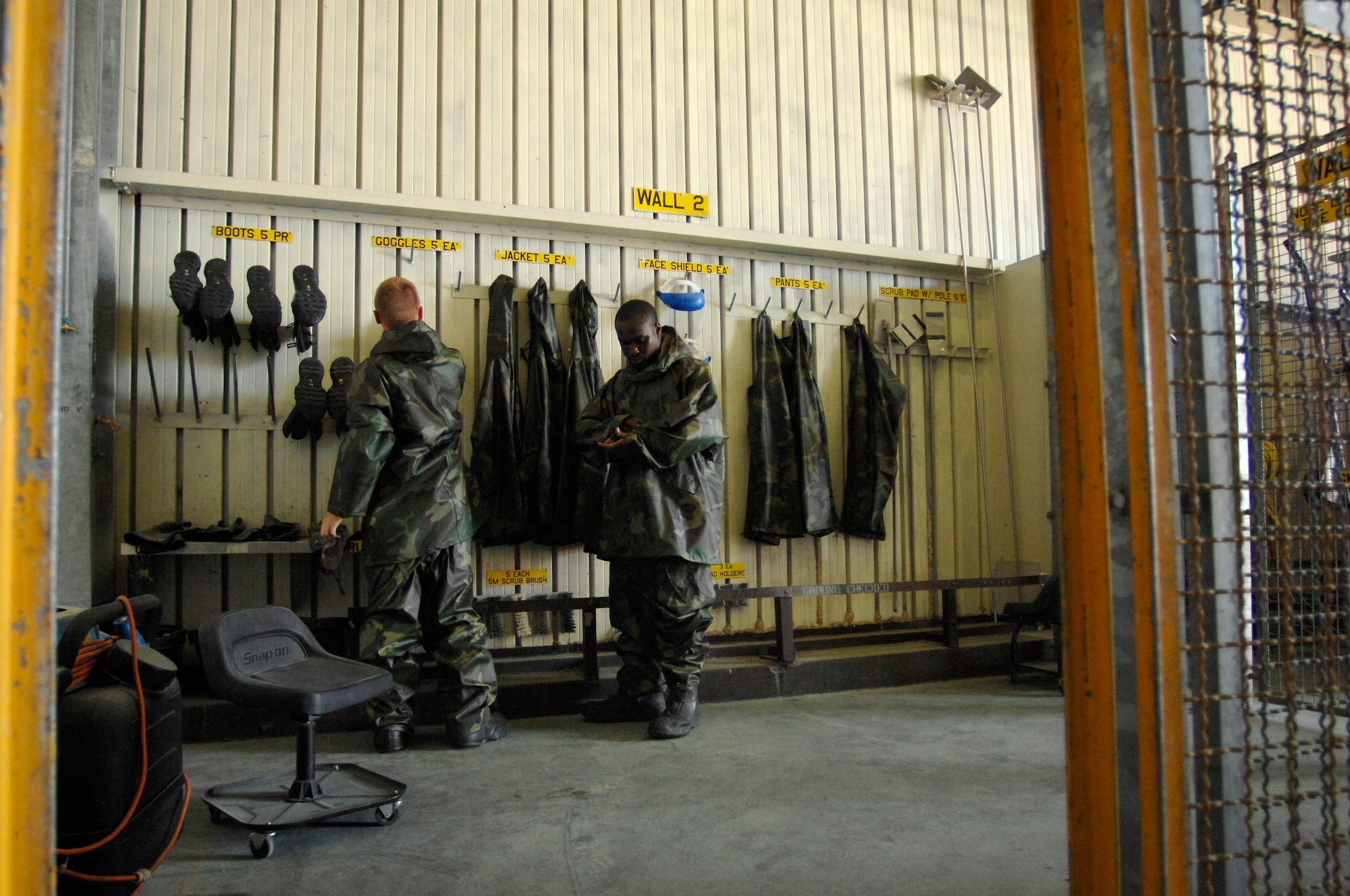 Airmen 1st Class Brandon Frazier and Tommy Ellerbe, 31st Aircraft Maintenance Squadron, cover their BDUs with personal protective equipment to keep them dry before they wash an F-16, Sept. 9 in the base wash rack. The Aviano F-16 fleet is routinely washed every six months or as needed to maintain professional looking and corrosion-free aircraft. (U.S. Air Force photo/Airman 1st Class Ashley Wood)