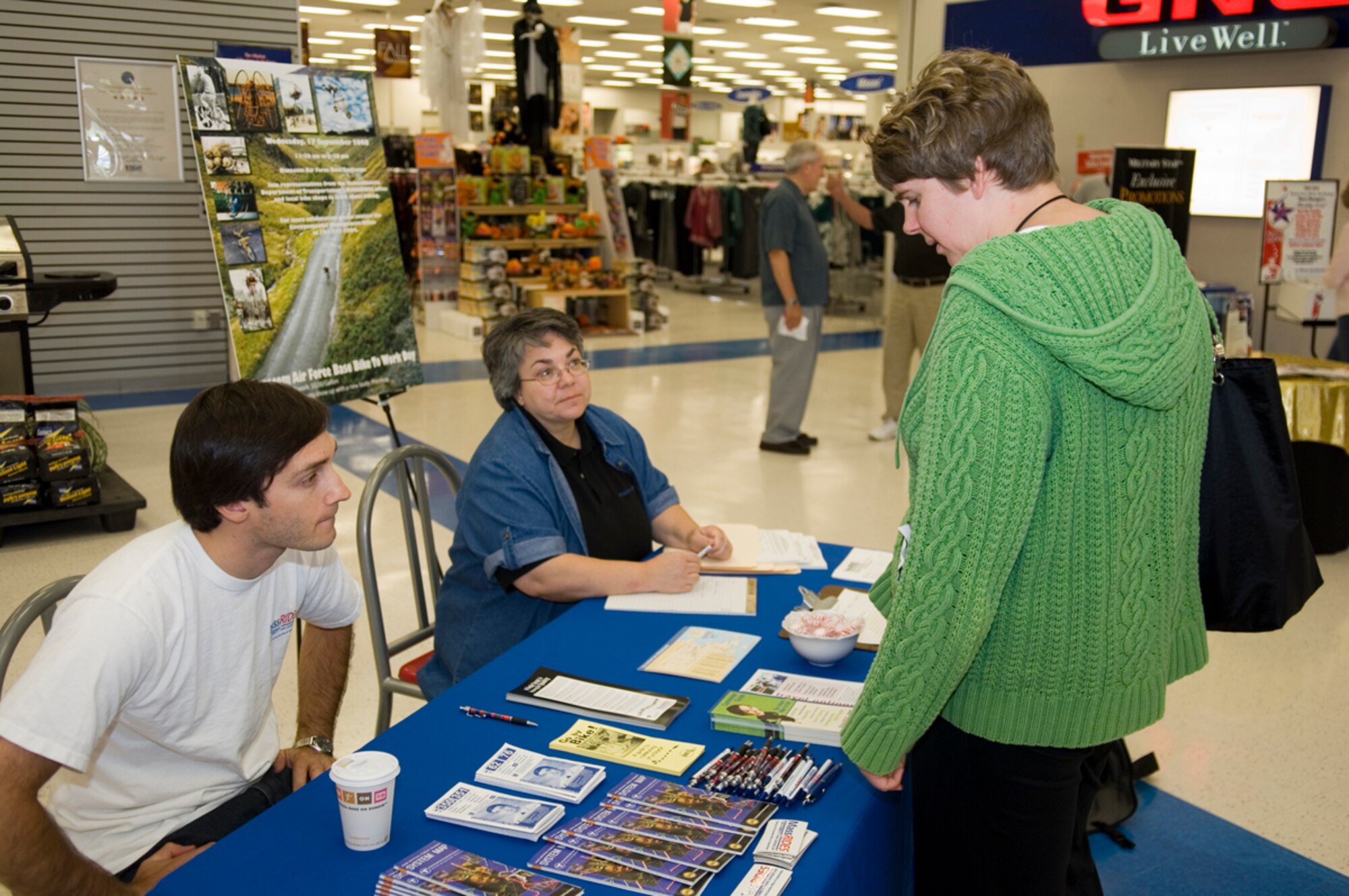 HANSCOM AFB, Mass. -- Holly Seiferth, 850th Electronic Systems Group contractor, peruses the Commuter Awareness Day tabled manned by Elliot Schmidt, outreach coordinator for the Massachusetts Department of Transportation's MASSRIDES office, and Linda Arpino, 66th Mission Support Group Environmental office, in the Base Exchange complex Sept. 10. Hanscom employees interested in public transportation or carpooling have several programs available. The Ride Matching program, which is run by the Environmental office, pairs employees with similar work schedules to facilitate carpooling. Vanpools are also available for larger commuter groups. Additionally, employees using public transportation may qualify for the Transportation Incentive Program -- a Department of Defense program that provides financial incentives to employees to encourage commuting by mass transportation. (U.S. Air Force photo by Rick Berry)