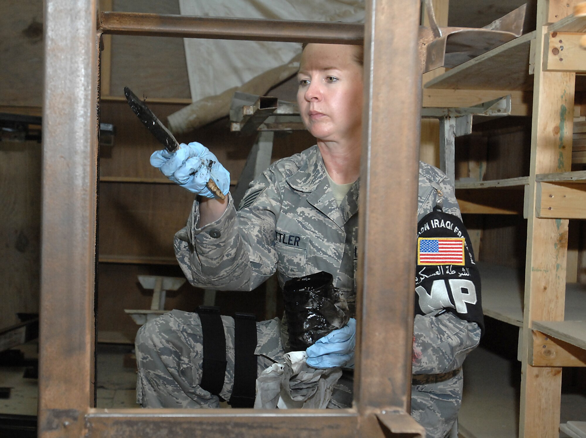 ALI BASE, Iraq -- Tech. Sgt. Kari Rattler, 407th Provost Marshal Office NCO in charge of reports and analysis, applies black lacquer to a steel desk frame Sept. 13, 2008. She and others here volunteered to refurbish 150 desks that, once finished, 450 students from two Muthanna Province elementary schools will receive "new" desks. Rattler, a native of Cherokee, N.C., is deployed from Edwards Air Force Base, Calif. (U.S. Air Force photo/Tech. Sgt. Francesca Popp)