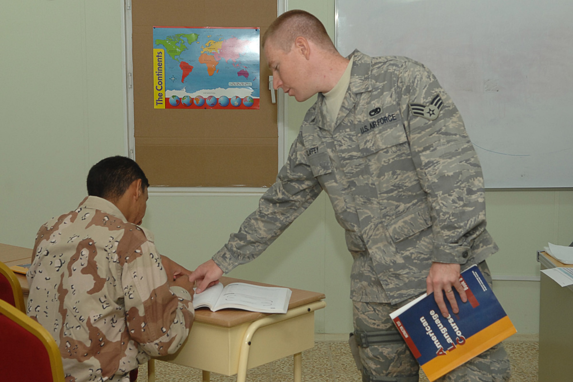 KIRKUK REGIONAL AIR BASE, Iraq -- Senior Airman Mitchell Claffey, 870th Air Expeditionary Advisory Squadron American Language Course instructor, assists an airman from the Iraqi air force during class here Sept 8.  Eighteen IqAF airmen graduated in an inaugural ceremony Sept 10.  The graduation is a big step for the IqAF and the U.S. Air Force since the program's start in April.  Airman Claffey is an avionics specialist deployed from RAF Lakenheath, England and calls Columbus, Ohio home.  (U.S. Air Force photo/Senior Airman Randi Flaugh)