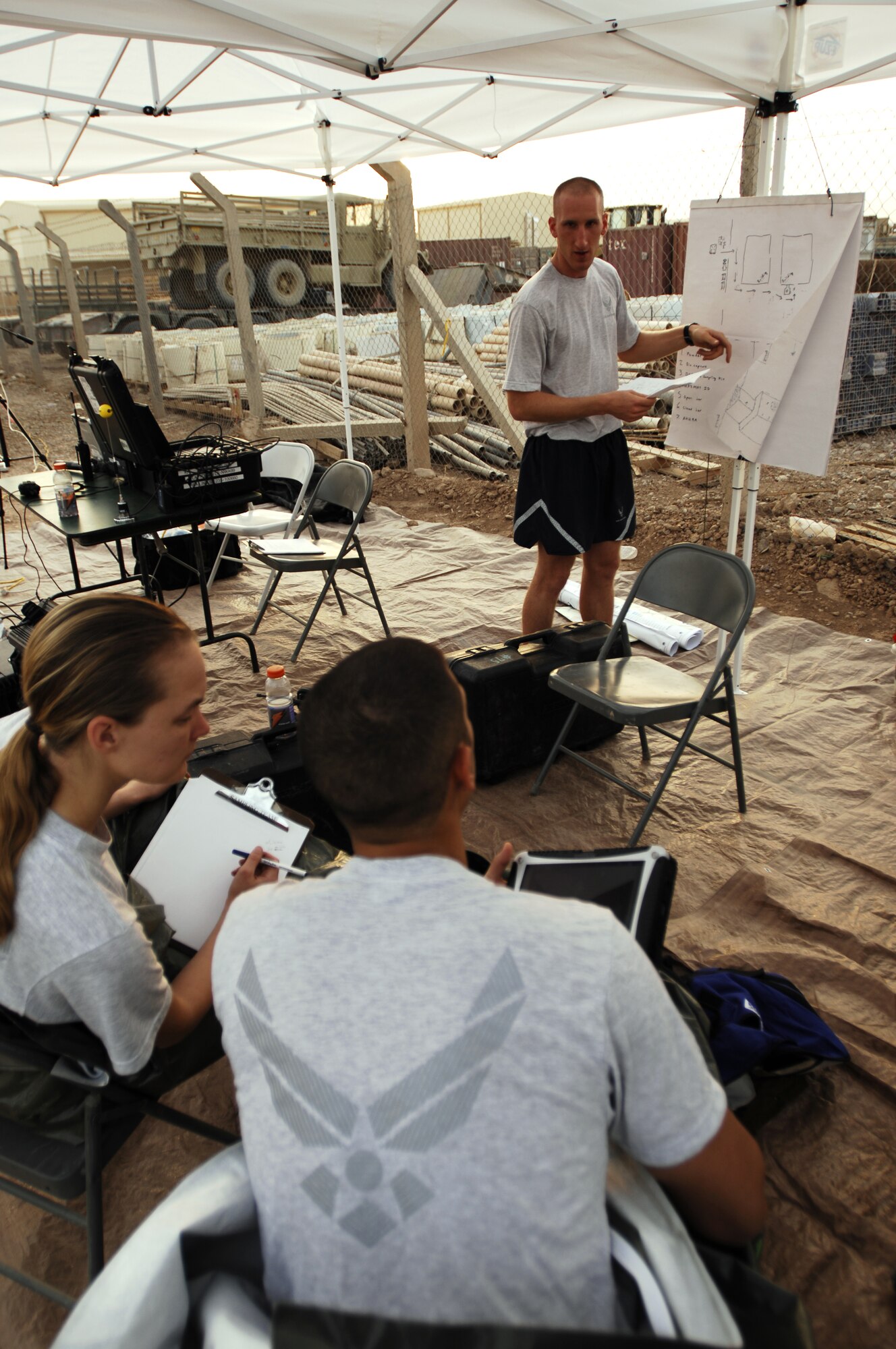 JOINT BASE BALAD, Iraq -- Senior Airman Heidi Williams (left) and Airman 1st Class Jacob John (right) are briefed by Senior Airman James Lawrence, an initial monitoring team member, on the layout of a simulated contamination area here Sept. 11. These 332nd Civil Engineer Squadron Emergency Management Flight Airmen conduct simulation exercises to practice their proficiency at responding to chemical, biological, radiological nuclear and environmental incidences. Lawrence is deployed from Eglin Air Force Base, Fla., and his hometown is Grayland, Mich. Williams is deployed from Beale Air Force Base, Calif., and her hometown is Plymouth, Ind. John is deployed from Eglin Air Force Base, Fla., and his hometown is Baton Rouge, La. (U.S. Air Force photo/Airman 1st Class Jason Epley)