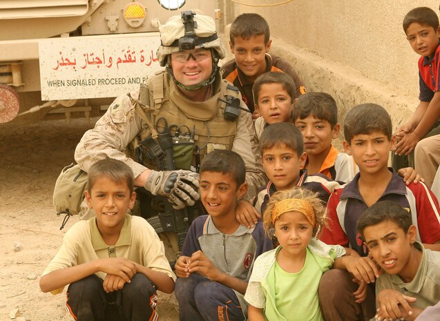 KARMAH, Iraq-Navy Chief Roger Buck, a 34-year-old battalion medical chief from Niceville, Fla., Task Force 1st Battalion, 3rd Marine Regiment, Regimental Combat Team 1, poses with Iraqi children at a combined medical engagement. Buck saved a boy's life in Karmah, Iraq, when the boy nearly drowned Sept. 28. He saw the near lifeless boy cradled in his father's arms and immediately reacted by administering CPR, saving the boyâ??s life. (Photo by Lance Cpl. Achilles Tsantarliotis)