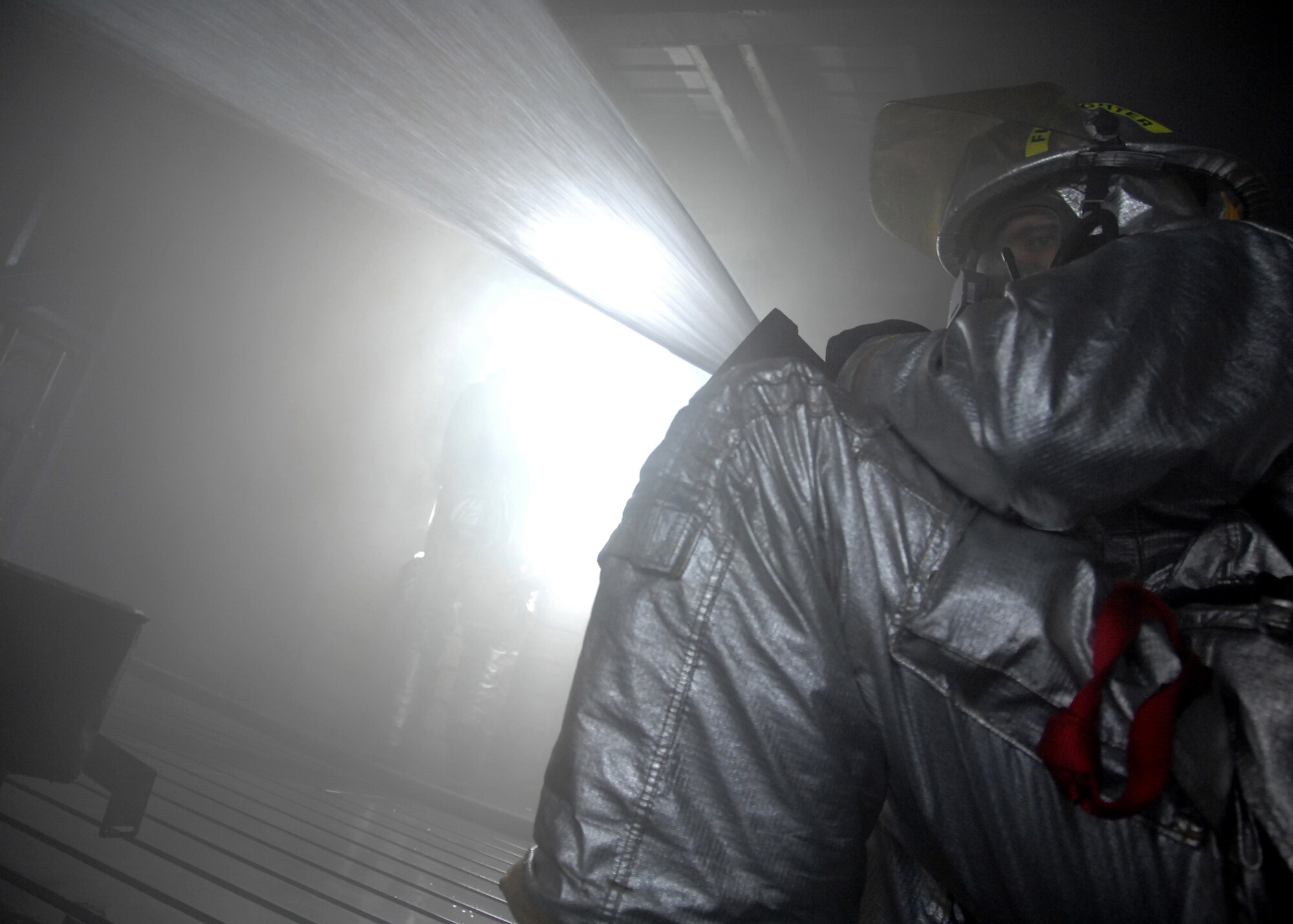 A firefighter from the 354th Civil Engineer Squadron fire protection flight, directs a jet of water during a training operation on Sept. 13, 2008, at the live fire training area on Eielson AFB, Alaska. The Firefighter focuses the jet of water toward beacons with red flashing lights, designed to emulate a fire. (U.S. Air Force photo by Airman 1st Class Willard E. Grande II)