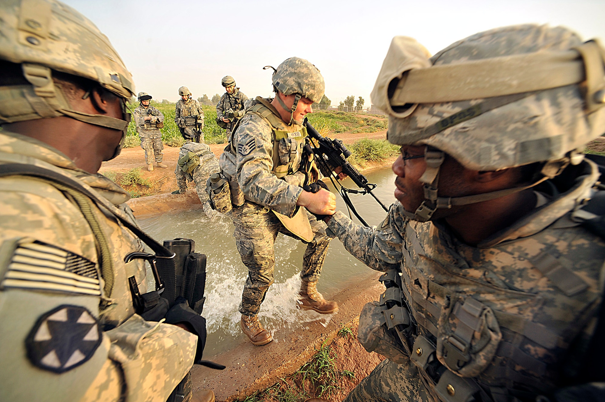Soldiers help Air Force Staff Sgt. Johnathon Krueger across a irrigation canal outside Joint Base Balad, Iraq, during Operation Lewis and Clark Sept. 11. Operation Lewis and Clark was a joint patrol in which Air Force security forces Airmen were introduced to Balad's outer perimeter. Since Americans began operating from Balad in 2003, the Army has been responsible for base security. The 332nd Expeditionary Security Forces Group will soon be the largest security forces unit deployed in combat to defend an air base since Vietnam. Sergeant Krueger is assigned to the 332nd Expeditionary Security Forces Squadron. (U.S. Air Force photo/Staff Sgt. Aaron Allmon)
