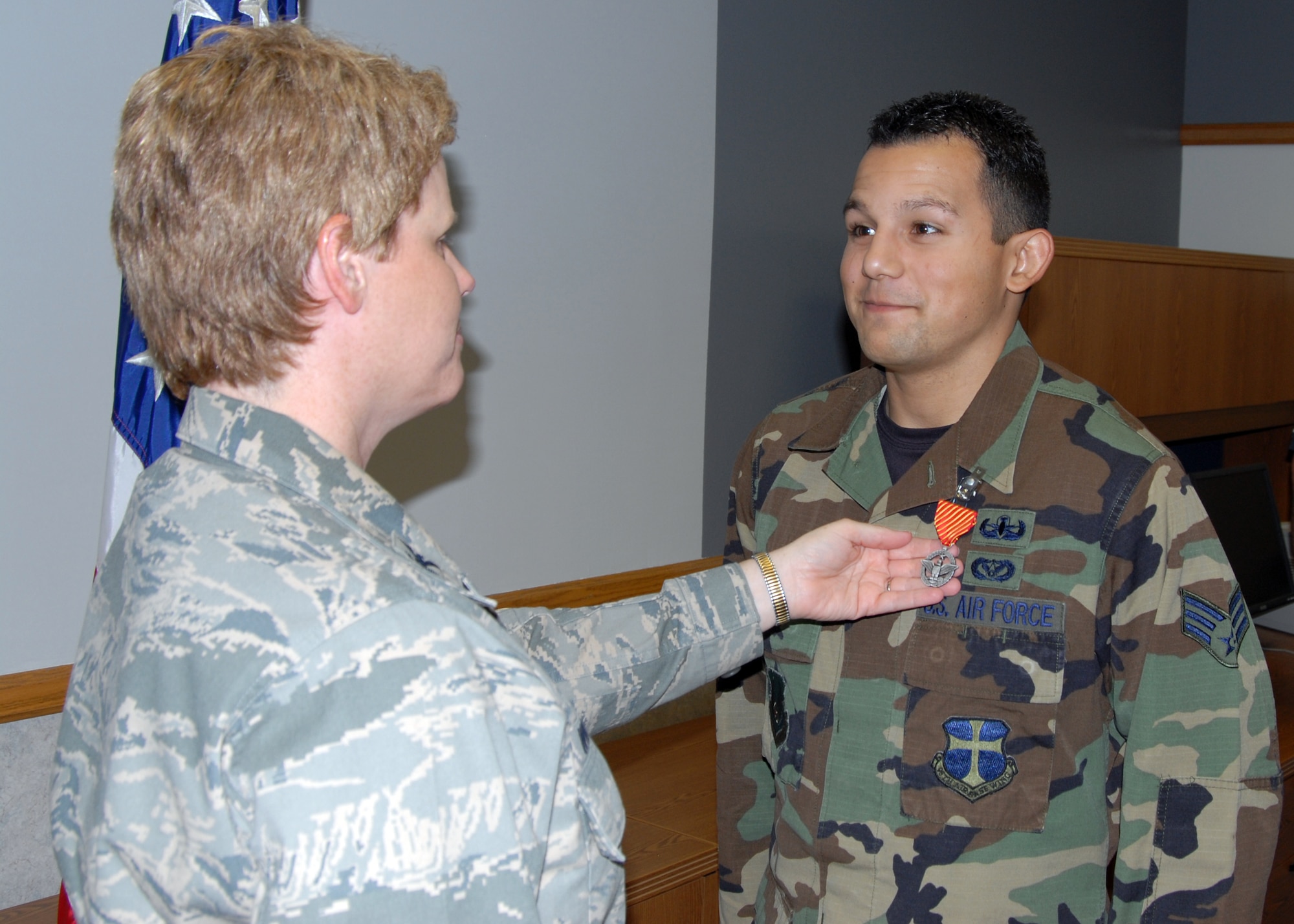 Col. Nancy Wharton, 95th Air Base Wing vice commander, presents the Air Force Combat Action Medal to Senior Airman Oscar Ortega, Explosive Ordnance Disposal Unit technician, during a ceremony at the Civil Engineering and Transportation Directorate Main Conference Center Sept.16. On Sept. 16, 2006, while deployed in support of Operation Iraqi Freedom, Airman Ortega and two other EOD technicians also from Edwards, Master Sgt. David Larriva and Staff Sgt. Nicholas Last, disarmed three improvised explosive devices in a kill zone after enduring gunfire from the enemy. Once they completed their reconnaissance for more IEDs, the Airmen gathered into their Humvee.  As soon as Airman Ortega, who was the driver, put their vehicle into reverse, another hidden IED exploded and launched them into the air.  The two sergeants survived, but Airman Ortega received some hearing damage.  (Air Force photo by Airman 1st Class William O’Brien) 