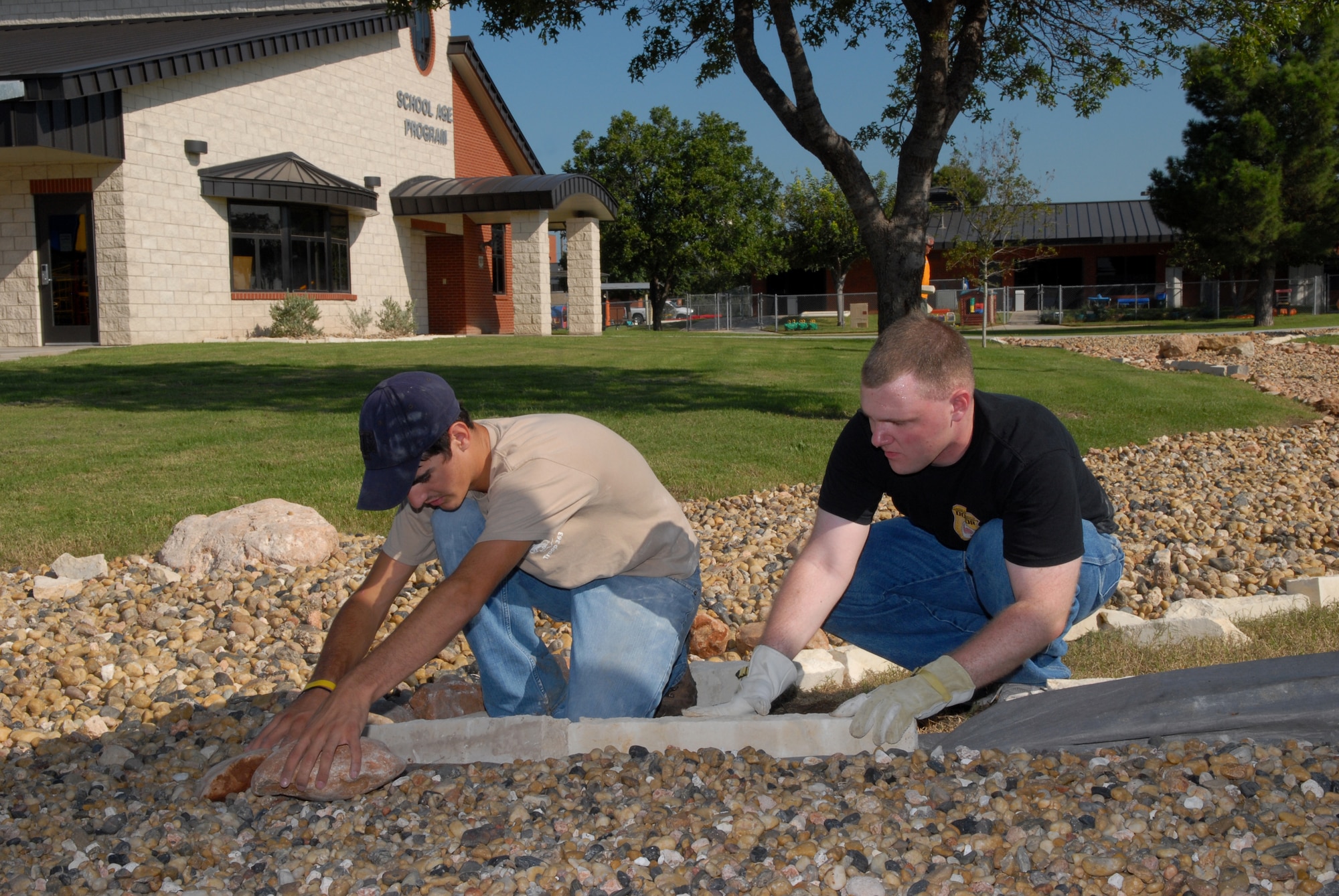 Taylor Cambre, a Boy Scout from Troop 363, and Senior Airman David Le Beau, 17th Civil Engineer Squadron readiness flight, lay border rock for the dry riverbed at the Goodfellow School-Age Facility Sept. 13. Taylor planned and led this undertaking as part of his Eagle Scout service project. Members of the 17 CES volunteered their time to help. (U.S. Air Force photo by Senior Airman Kasabyan Musal)