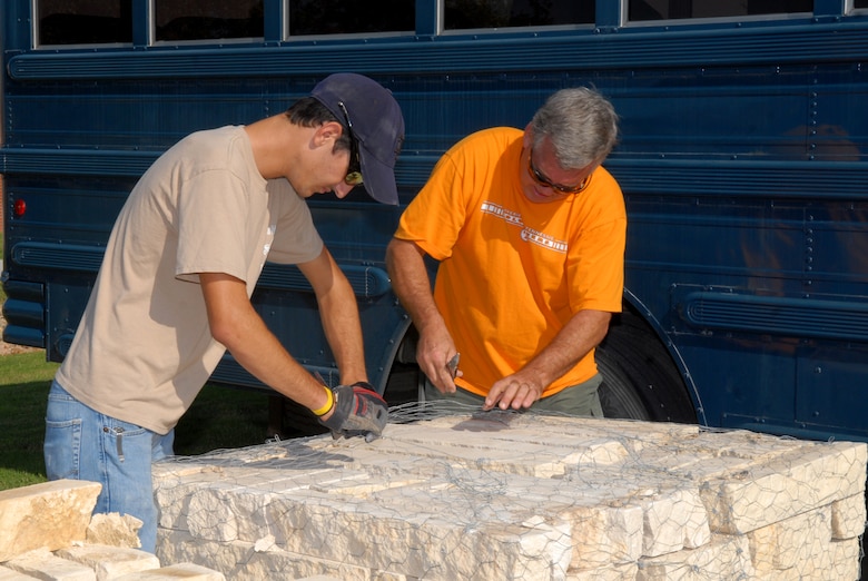 Taylor Cambre, a Boy Scout from Troop 363, and Mike Noret, 17th Civil Engineer Squadron deputy base civil engineer, unpack border rock for the dry riverbed at the Goodfellow School-Age Facility Sept. 13. Taylor planned and led this undertaking as part of his Eagle Scout service project. Members of the 17 CES volunteered their time to help. (U.S. Air Force photo by Senior Airman Kasabyan Musal)