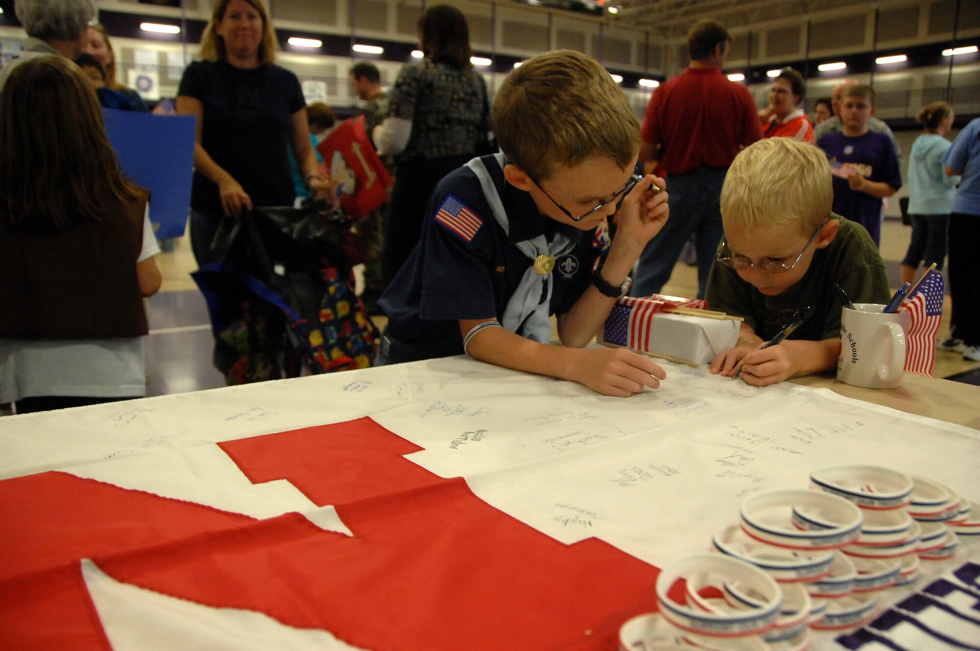 OFFUTT AIR FORCE BASE, Neb.--Two Bellevue children sign a Nebraska flag to send to military members overseas while attending Bellevue’s third annual America Supports You Freedom Walk Sept. 11 at the Bellevue Lied Center. America Supports You is a Department of Defense program that recognizes citizen’s support for the military and communicates that support to service members at home and abroad. (U.S. Air Force Photo By Josh Plueger) 
