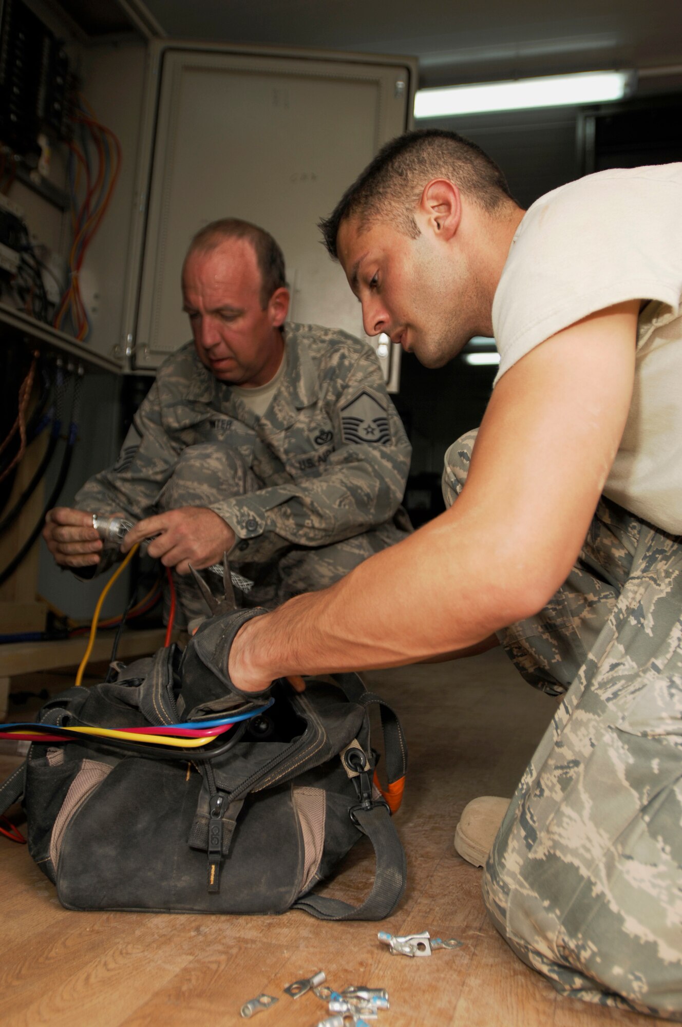 JOINT BASE BALAD, Iraq - Staff Sgt. Rocky Edwards, an electrical systems craftsman assigned to the 332nd Expeditionary Civil Engineer Squadron, retrieves tools to cut electrical wires that will be installed onto a circuit breaker as Master Sgt. Rich Winter removes a stress relief connector from wires here Sept. 9. Edwards and Winter, the 332nd ECES electrical NCO in charge, installed power to a new trailer that will be used by the 332nd Expeditionary Security Forces Group as a workspace for the Air Force's assumption of Joint Base Balad's security. Edwards is deployed from Cannon Air Force Base, N.M. Winter is deployed from McChord Air Force Base, Wash., and is hometown is Pittsburgh. (U.S. Air Force photo/Airman 1st Class Jason Epley)