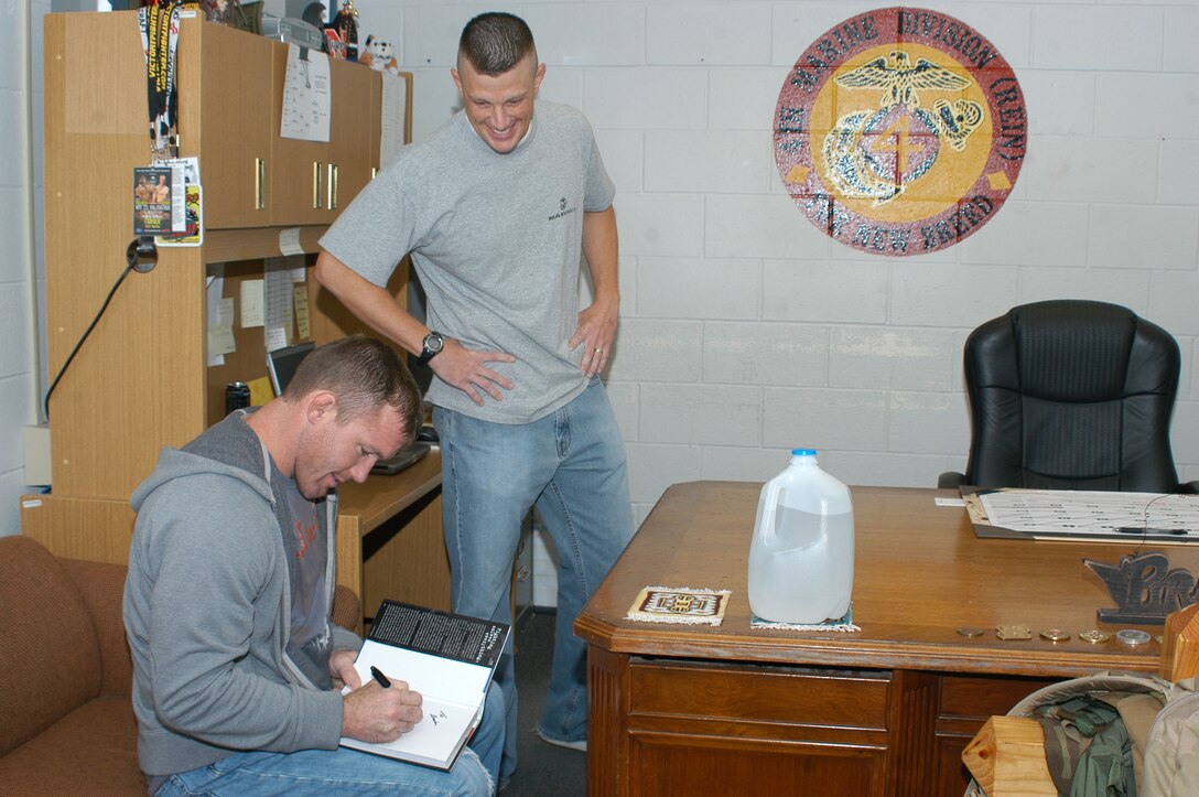 Ultimate Fighting Championship fighter Matt Hughes signs a copy of his book for Capt. Brandon Cooley, instructor-inspector for Engineer and Maintenance Co. Hughes was one of two fighters to visit the reserve center and acted as a guest coach for the two fighters.