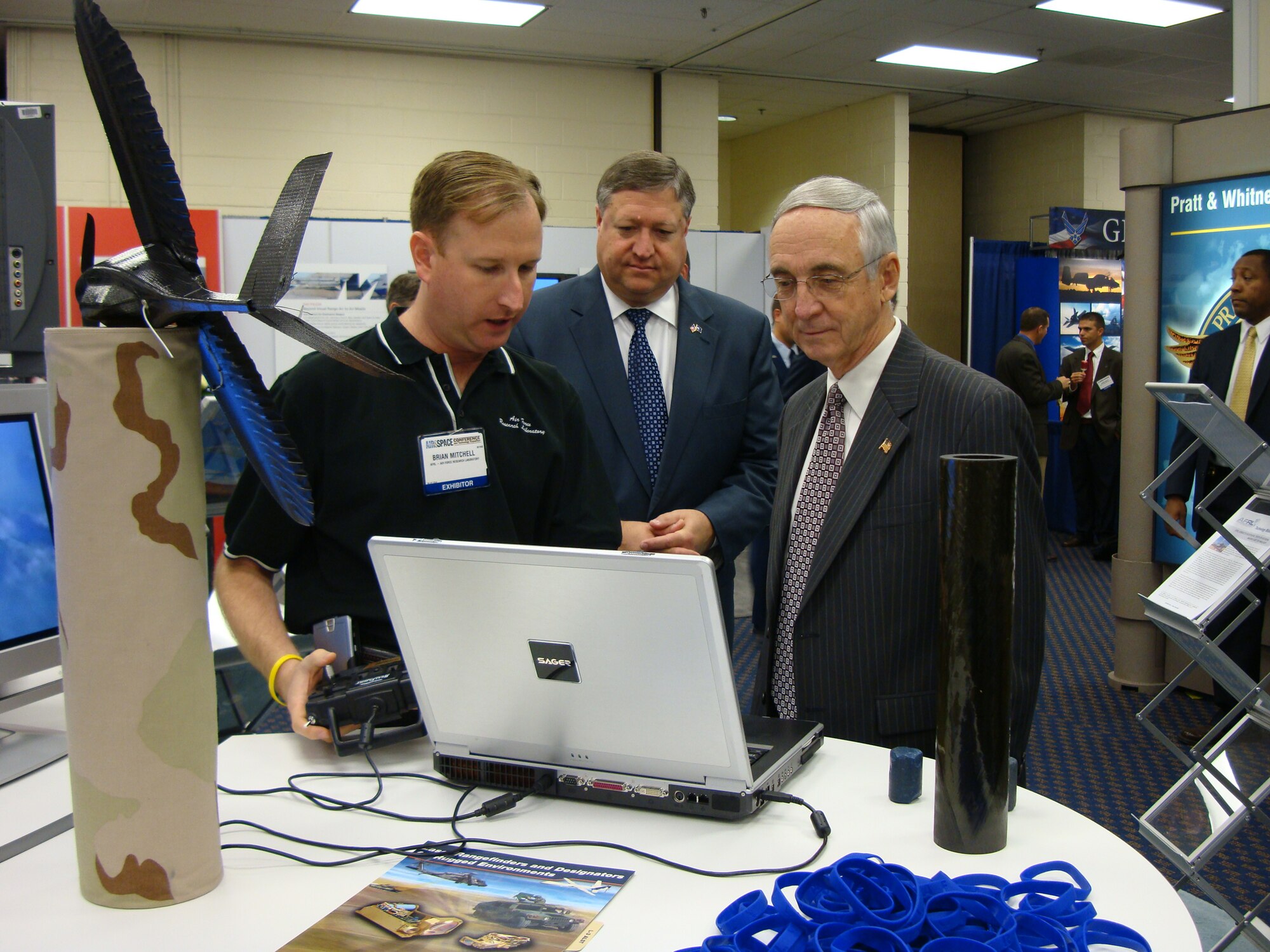 Deputy Secretary of Defense, Gordon England (right), Deputy Secretary of Defense, and Michael Donnelly (center), Secretary of the Air Force, listen to Brian Mitchell, Air Force Research Laboratory Munitions Directorate, as he describes solutions being developed for the problem of helicopter brownout at the national Air Force Association conference in Washington D.C. Sept. 15 through 17. (U.S. Air Force photo by Mike Wallace)
                               