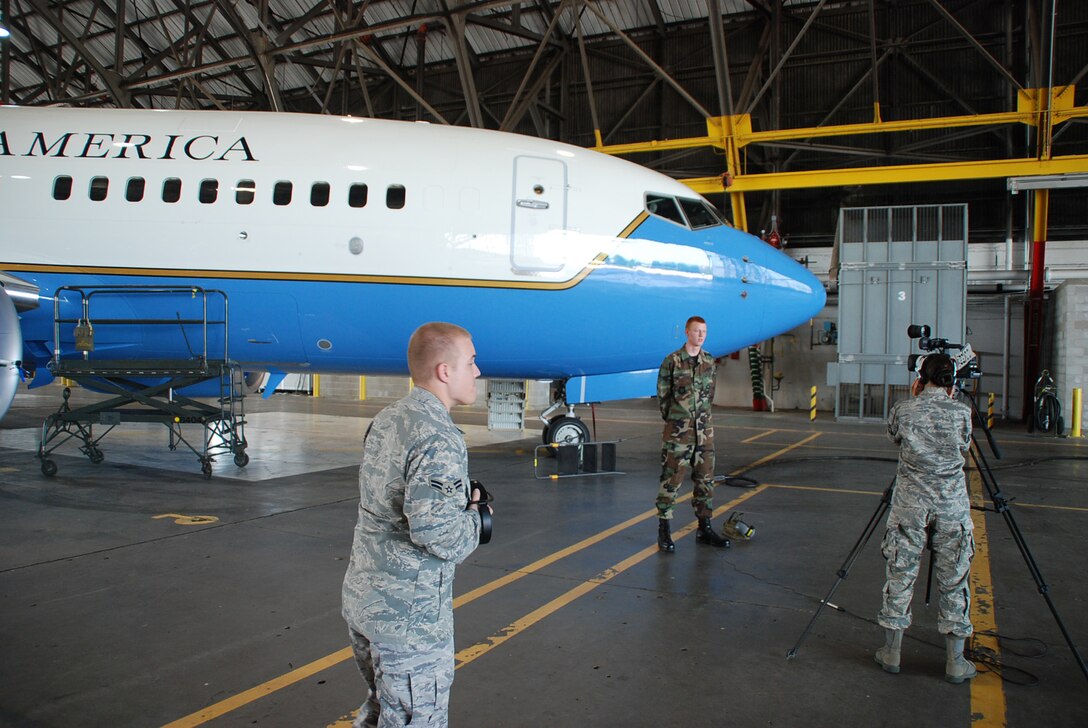 Airman First Class Jacob Schnauber, from the 932nd Airlift Wing Maintenance Group, watches from the sidelines as his fellow Airman First Class, Steve Kempker, is interviewed by the public affairs office during a documentary paying tribute to the work of the maintainers at the Air Force Reserve wing. U.S. photo by Maj. Stan Paregien

